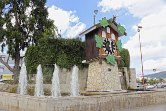 A cuckoo clock and fountain in a public square.
