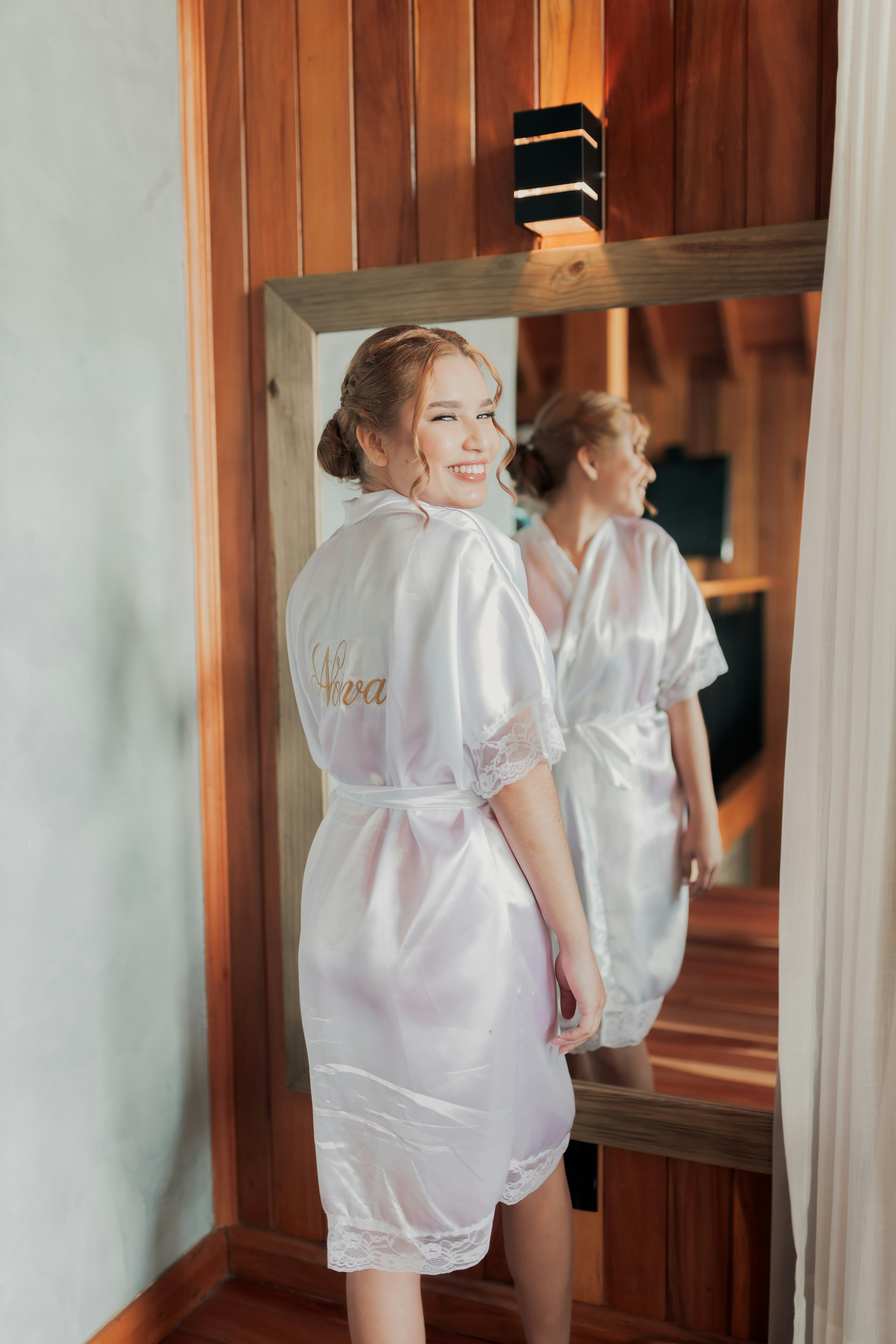 La sposa felice sorride allo specchio prima del suo matrimonio.