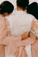 Bride embraces her bridesmaids in preparation.
