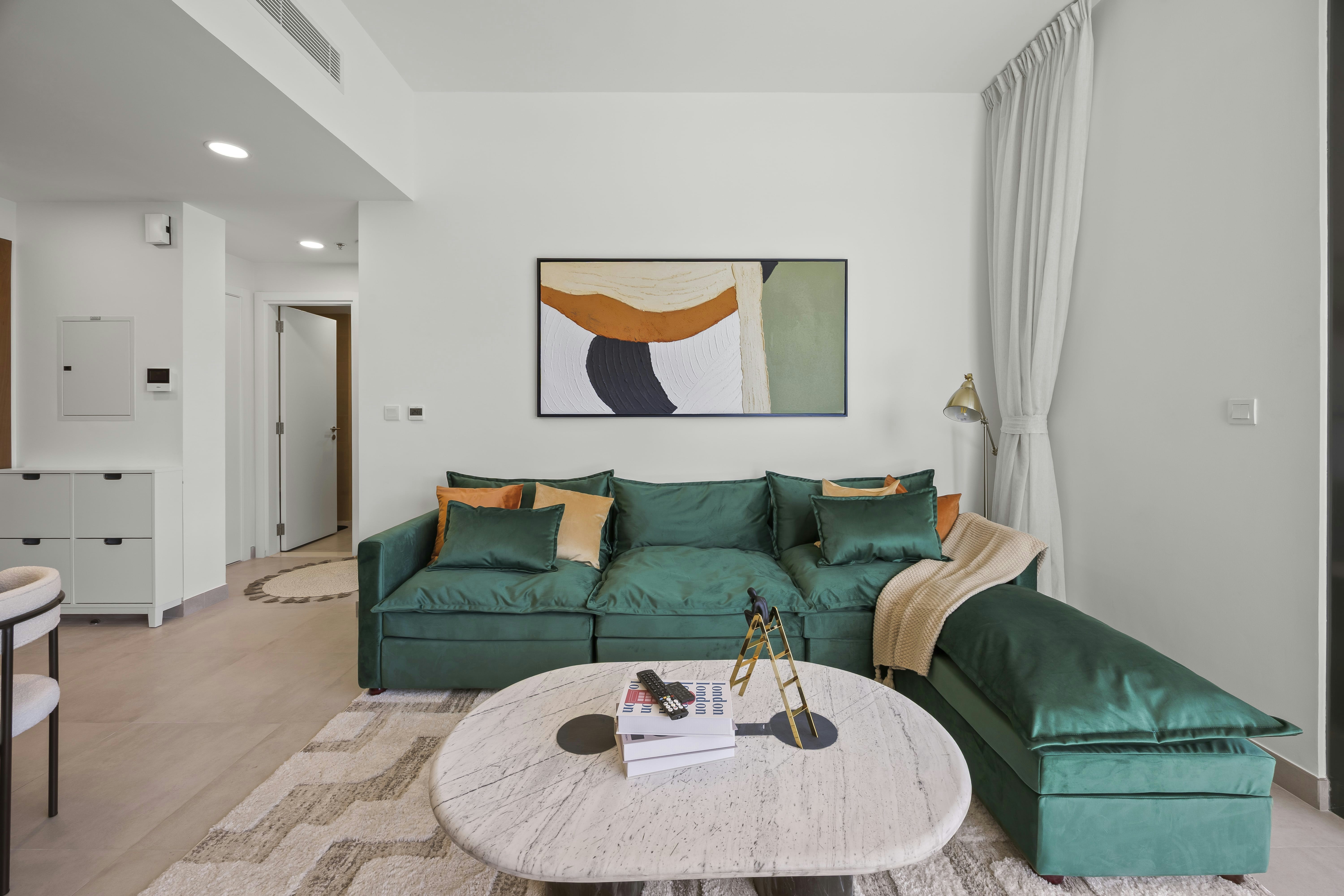 A modern living room with green sofa and art.