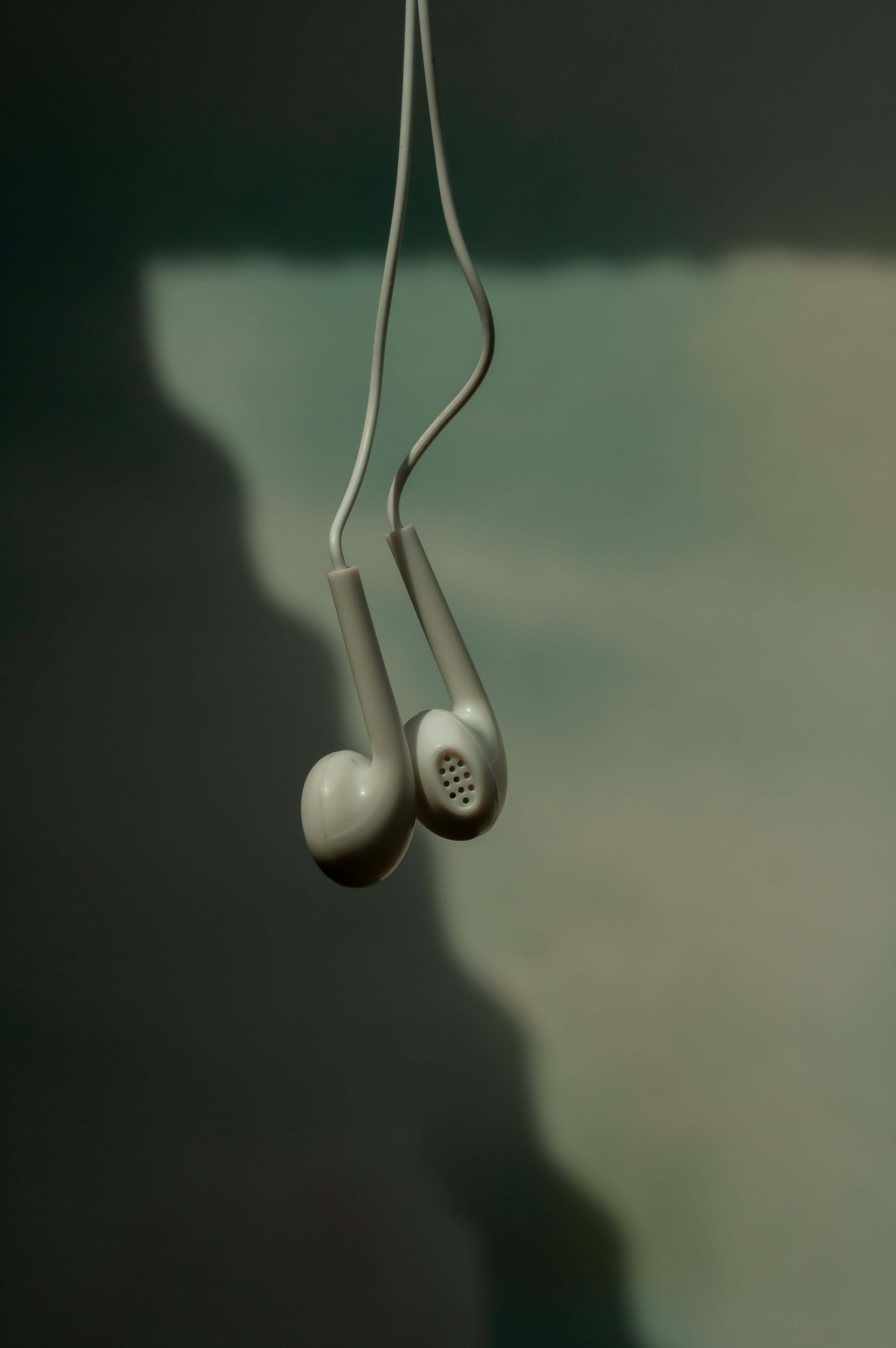 White earbuds hang in the air.