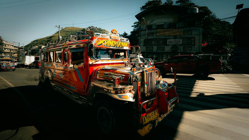 A brightly painted Filipino Jeepney bus driving through a city street, the same style of vehicle featured at the Golden Knights Filipino Heritage Knight photo spot