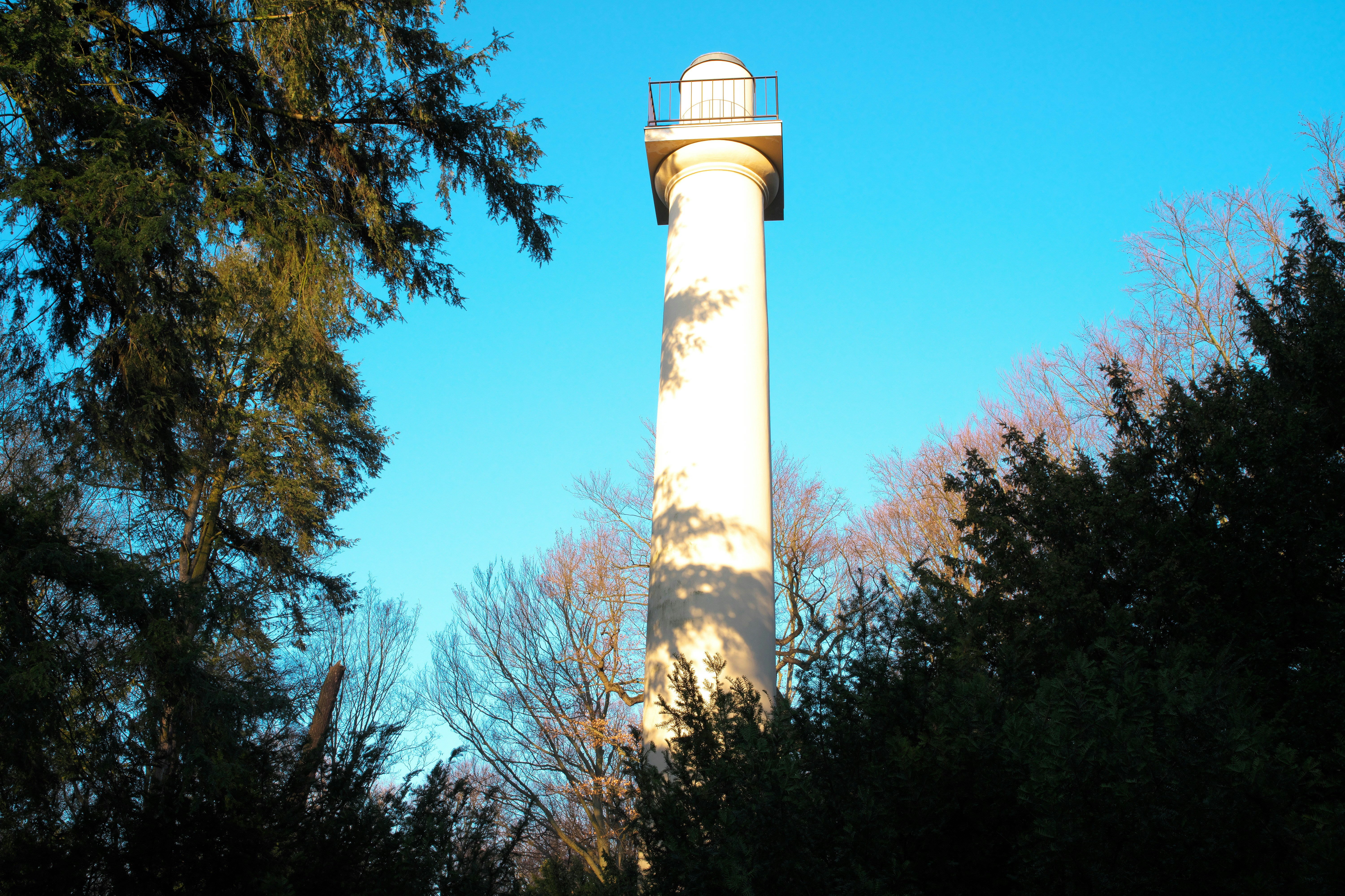 A tall, white column stands against a blue sky.