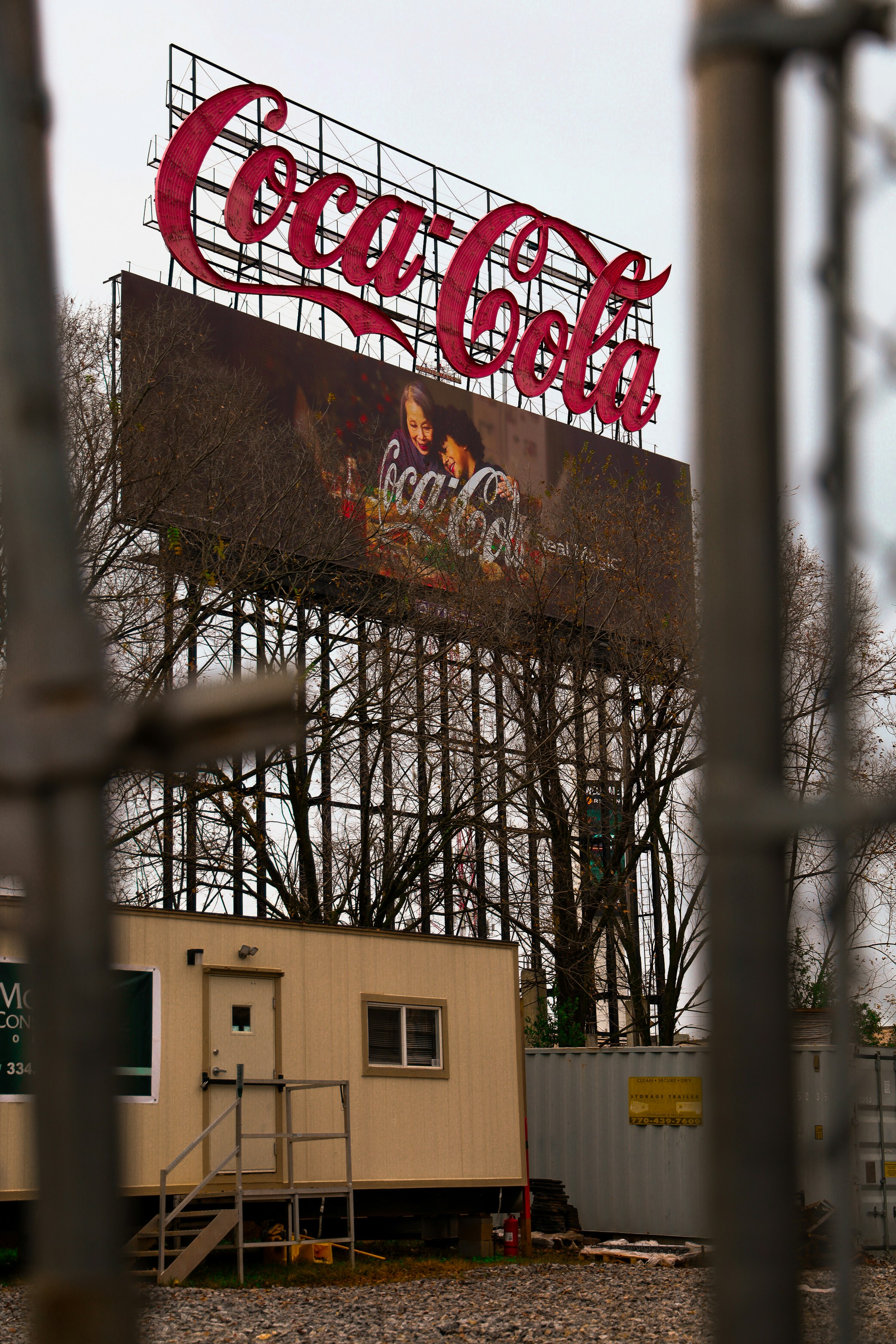 A large coca-cola sign stands tall outdoors.