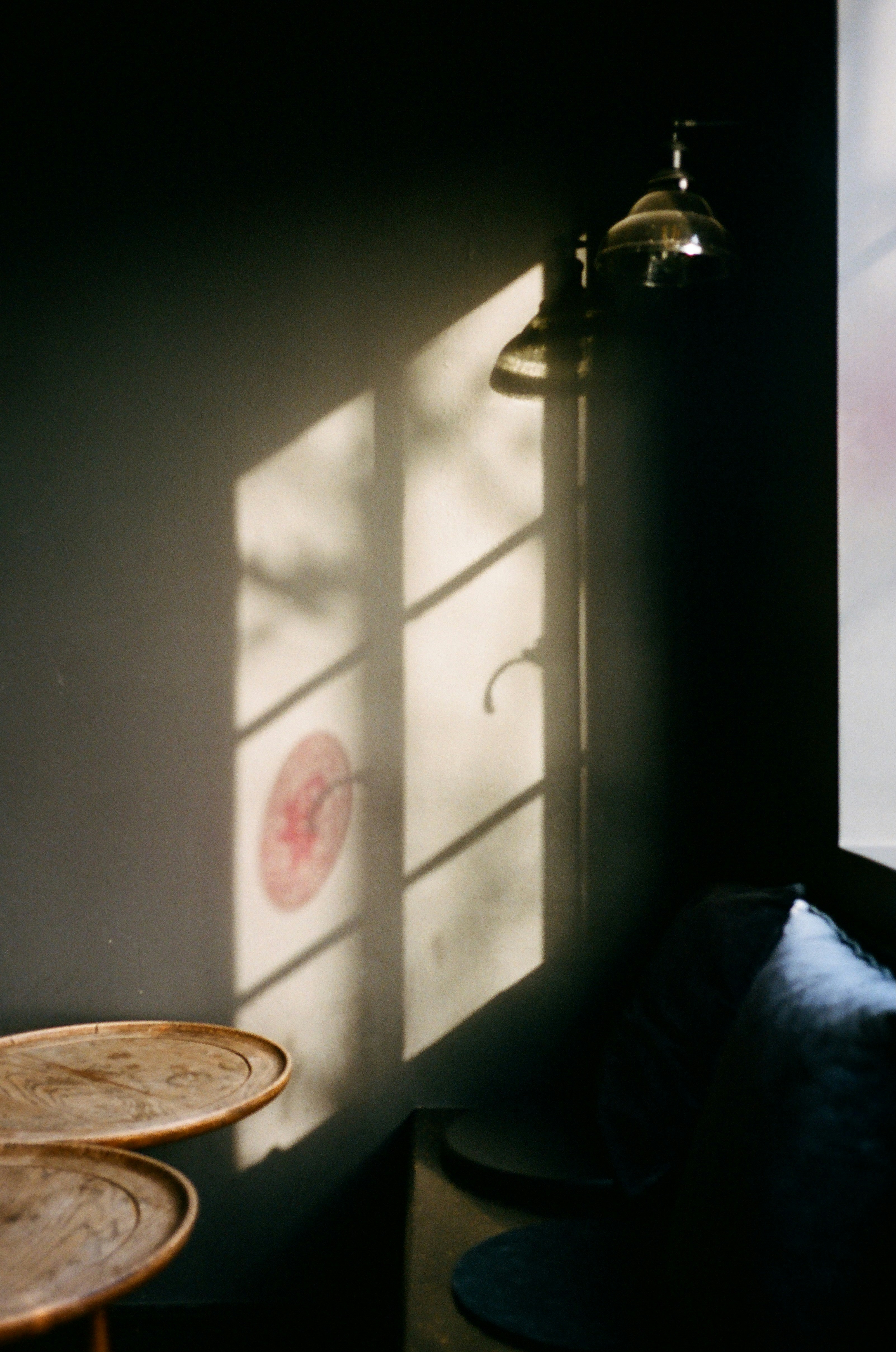 Sunlight casts shadows on a wall in a room.