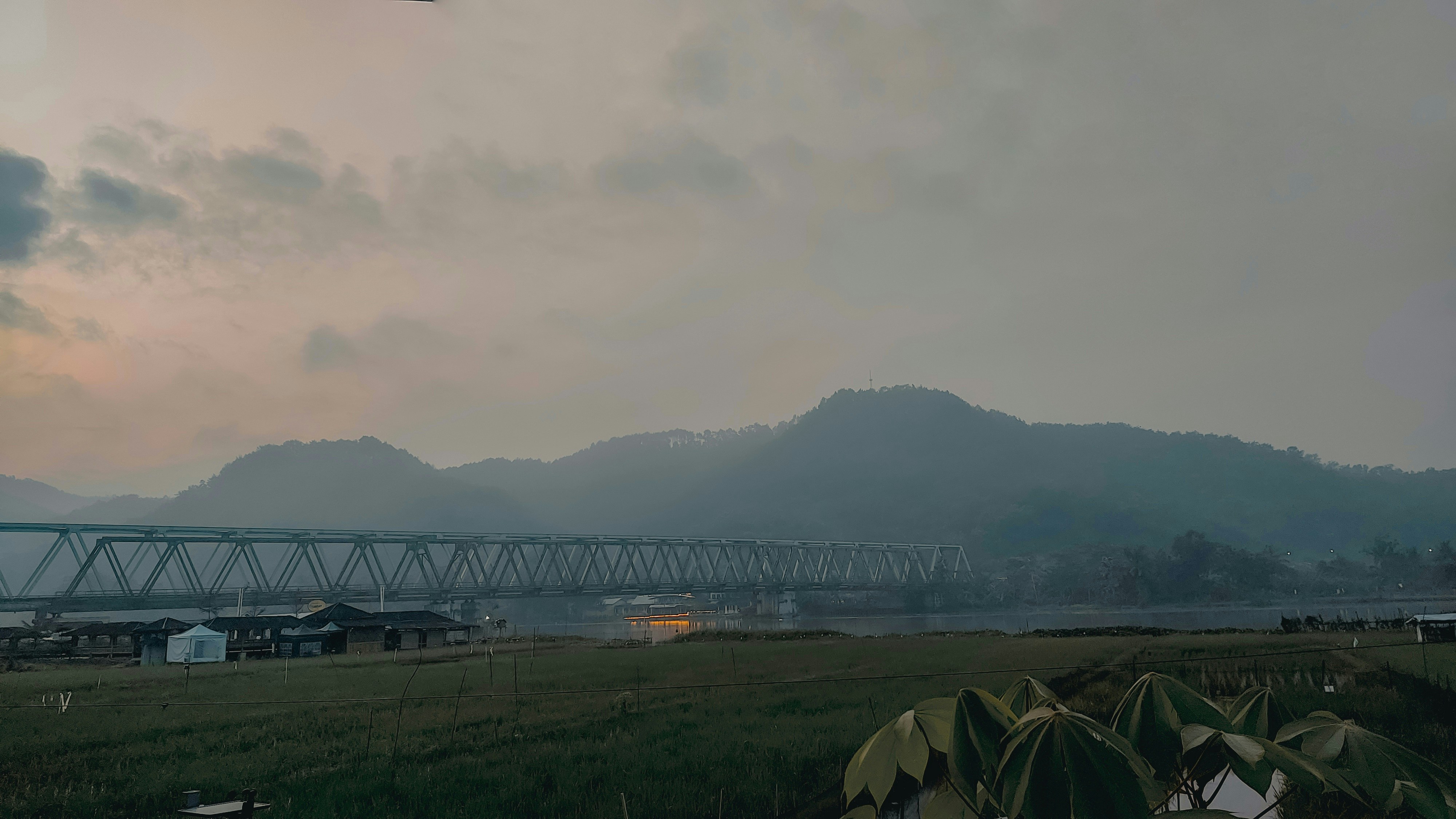 Mountains and bridge under a cloudy sky.