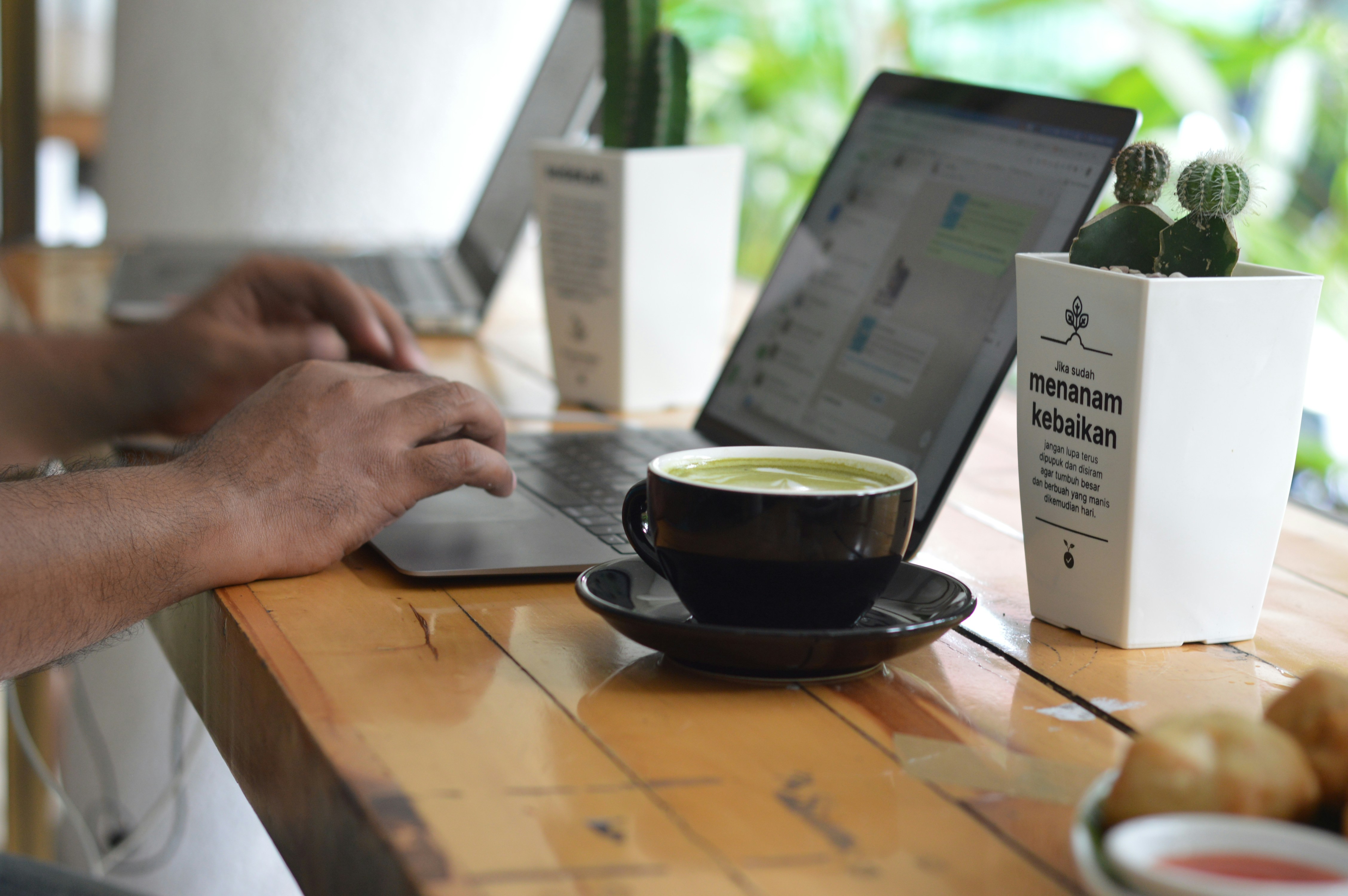 Person working on a laptop with a cup of tea.