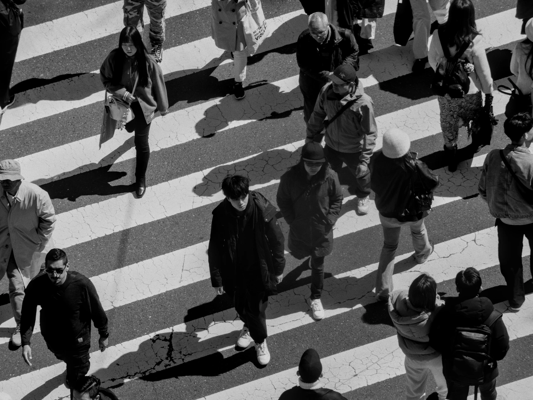 A solitary figure standing in a busy crosswalk crowd