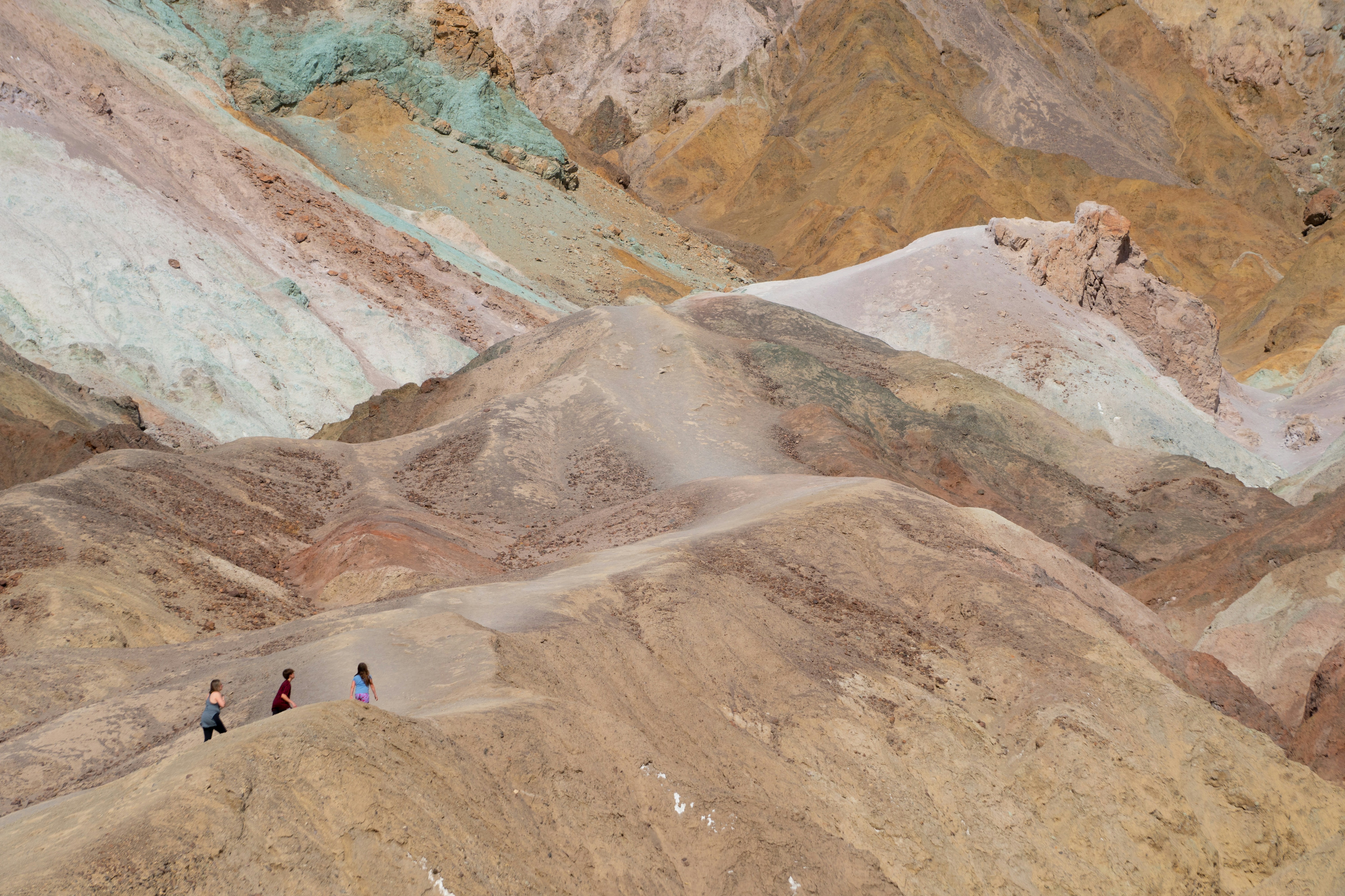 People walk along a colorful canyon ridge.