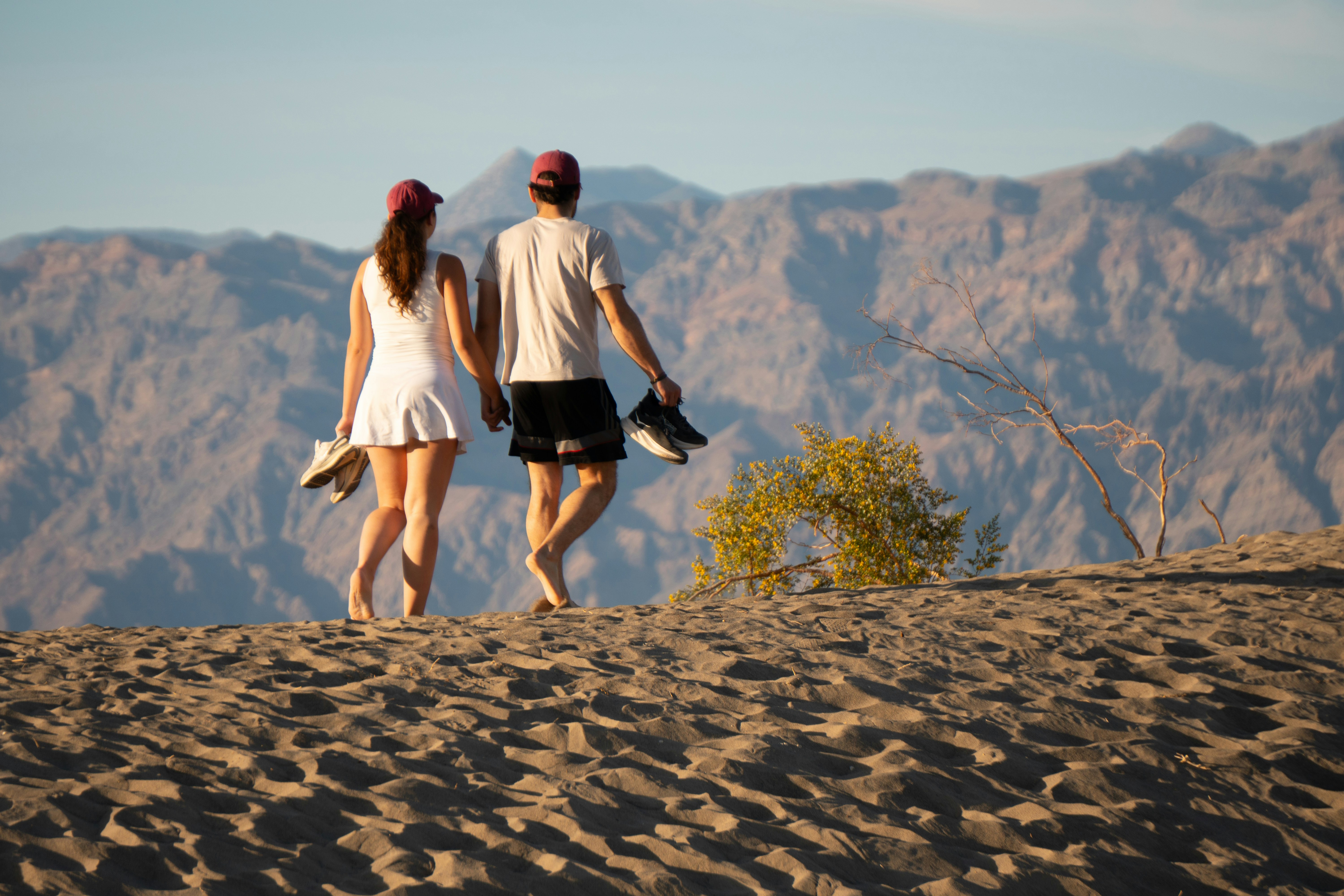 Couple walking barefoot on a sandy dune.
