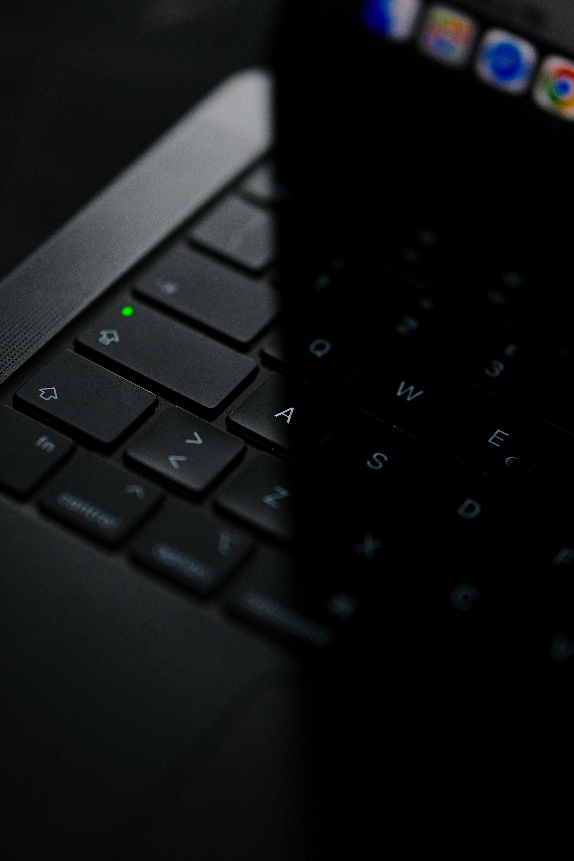 A laptop's keyboard is partly obscured by a phone.