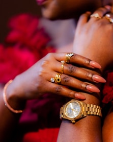 A hand showcases jewelry and a gold watch.