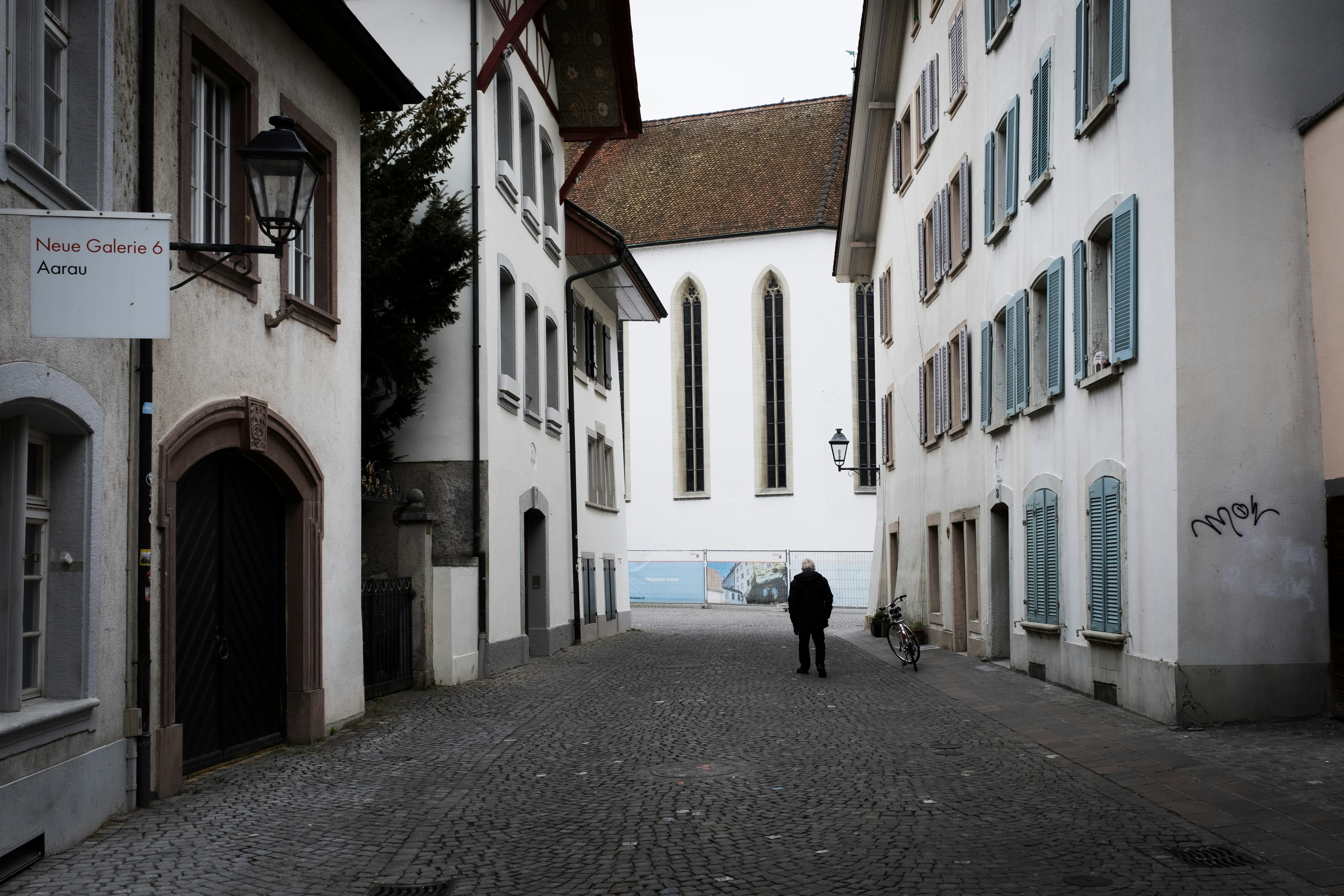 A person walks down a stone alley.