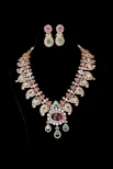 Elegant necklace and earrings against a black background.