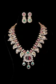 Elegant necklace and earrings against a black background.