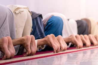 People are praying in a row on the floor.