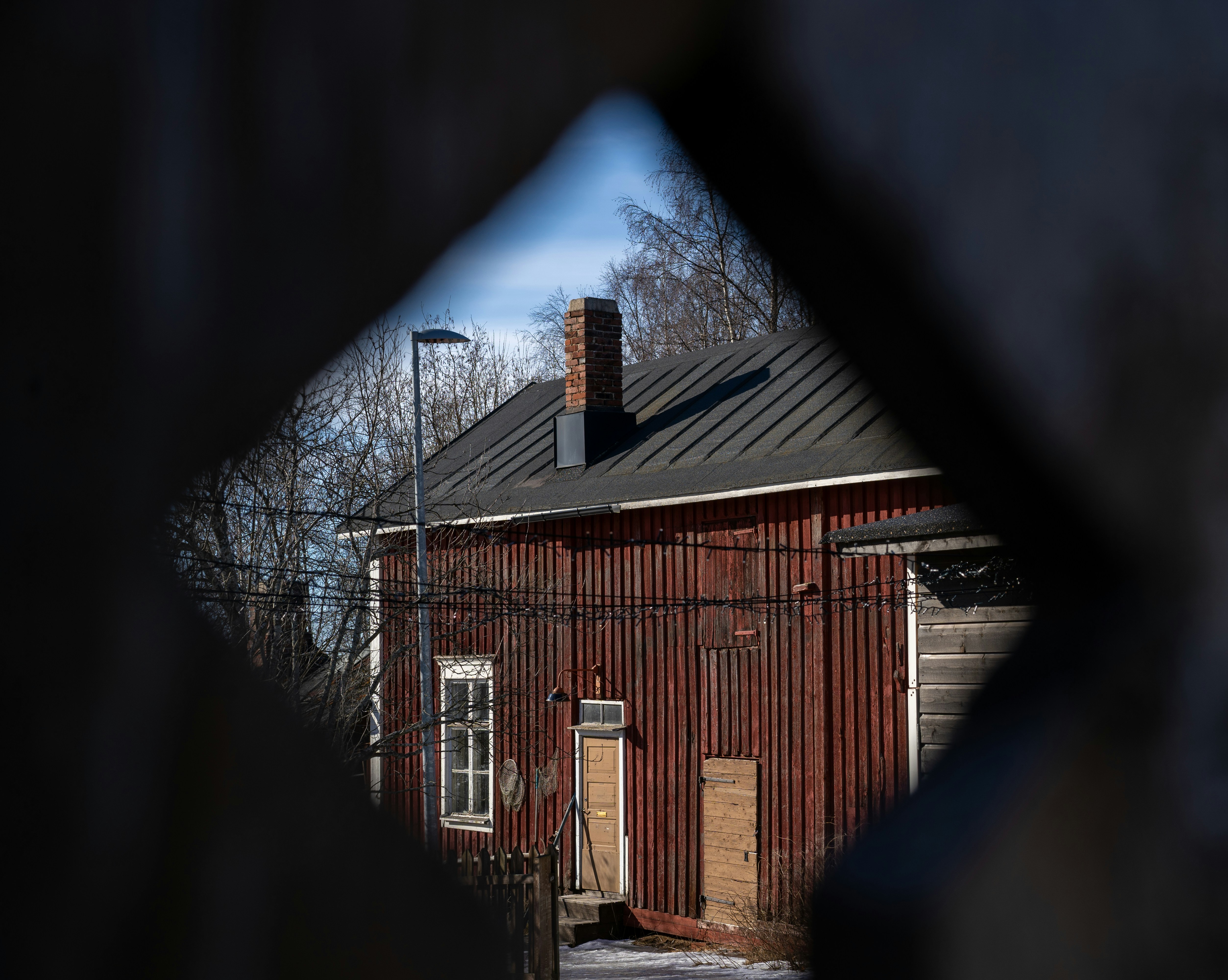 A weathered red building is framed by a diamond.