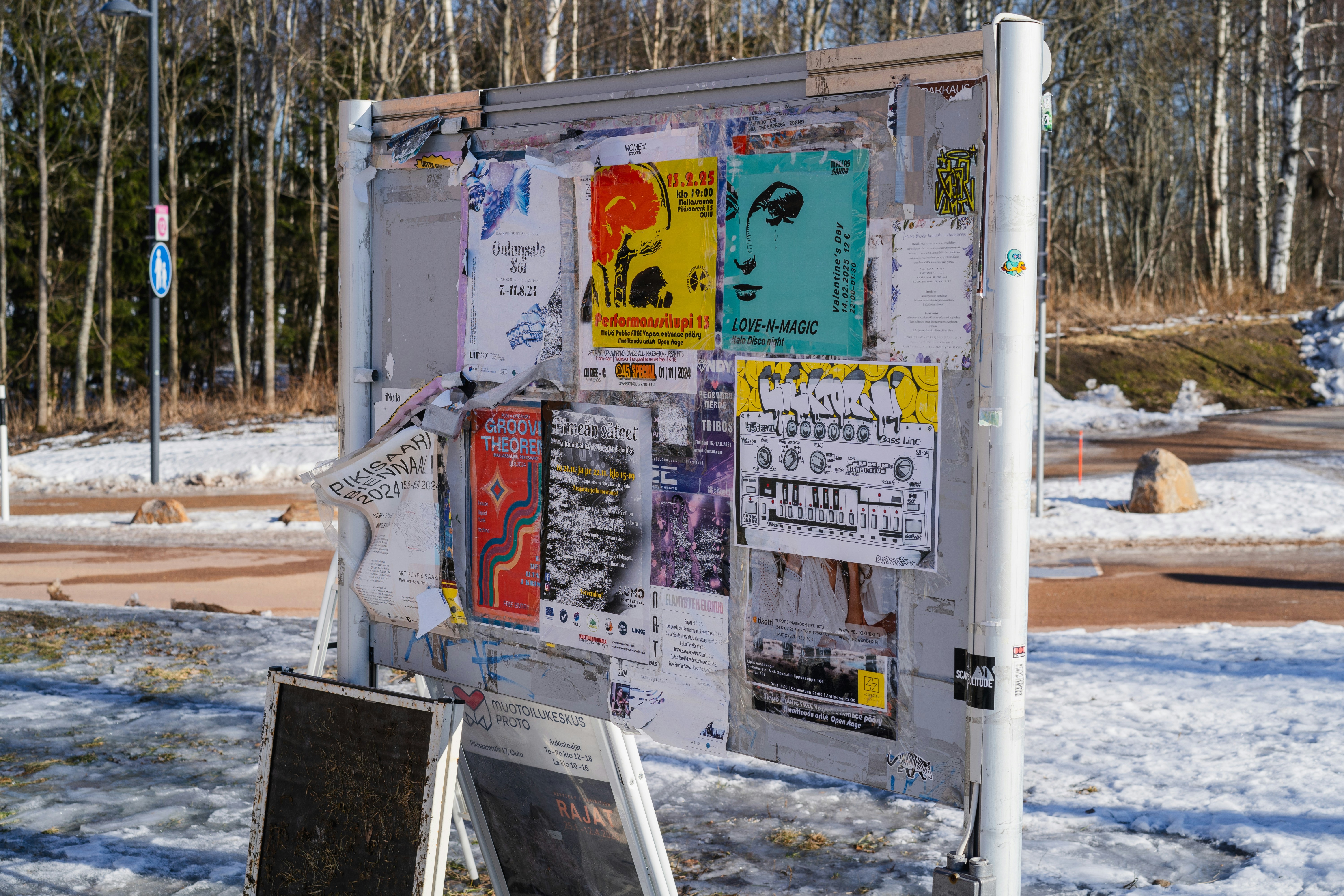 A bulletin board with flyers outdoors.