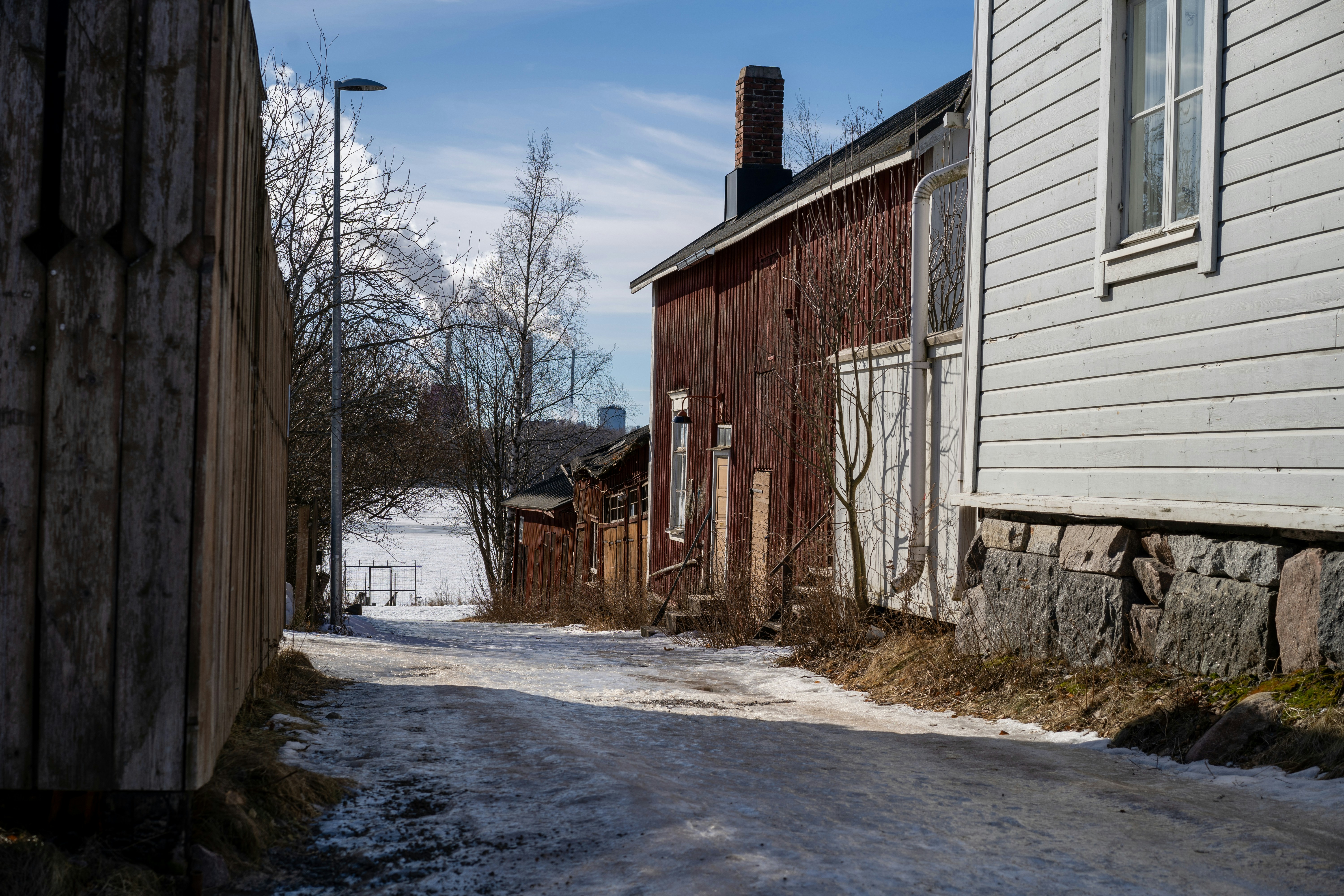 A snow-covered alley leads past old buildings.