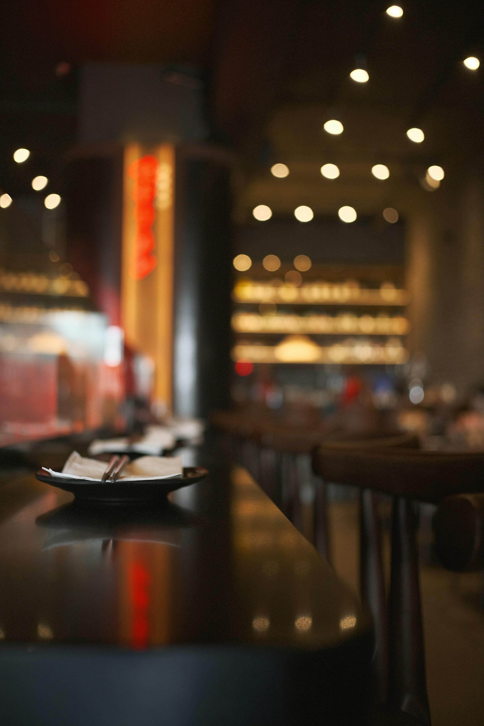 A restaurant's bar top with plates and chopsticks.