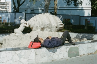 Person resting near a sculpture in a park.