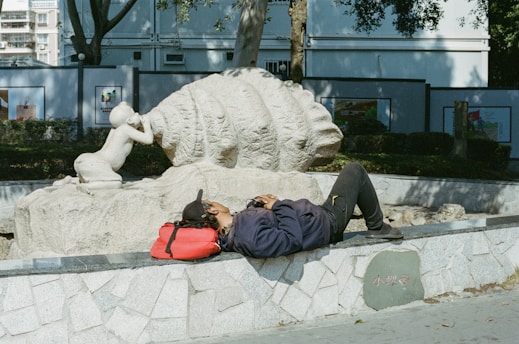 Person resting near a sculpture in a park.