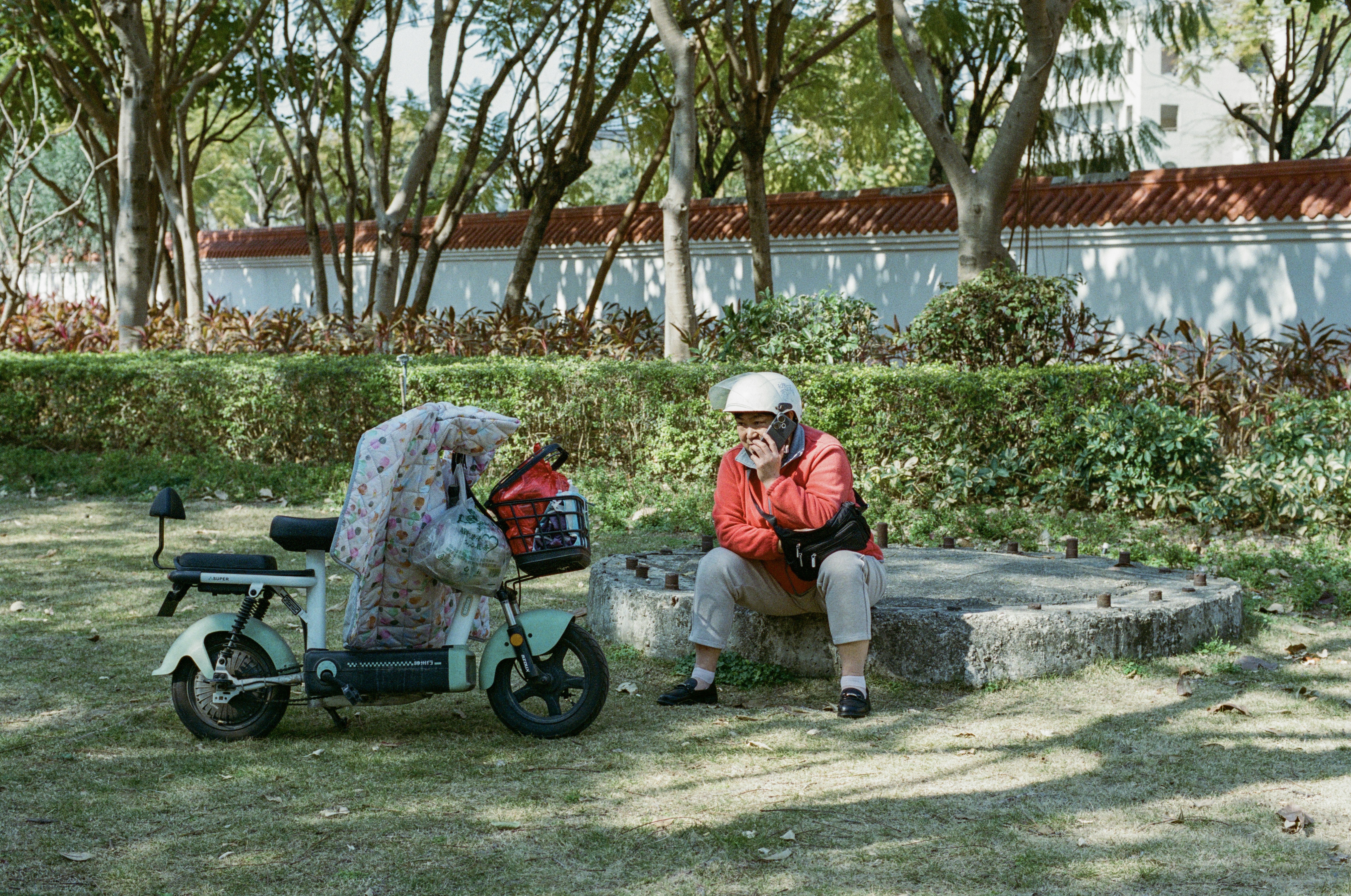 Woman rests by her scooter in a park.