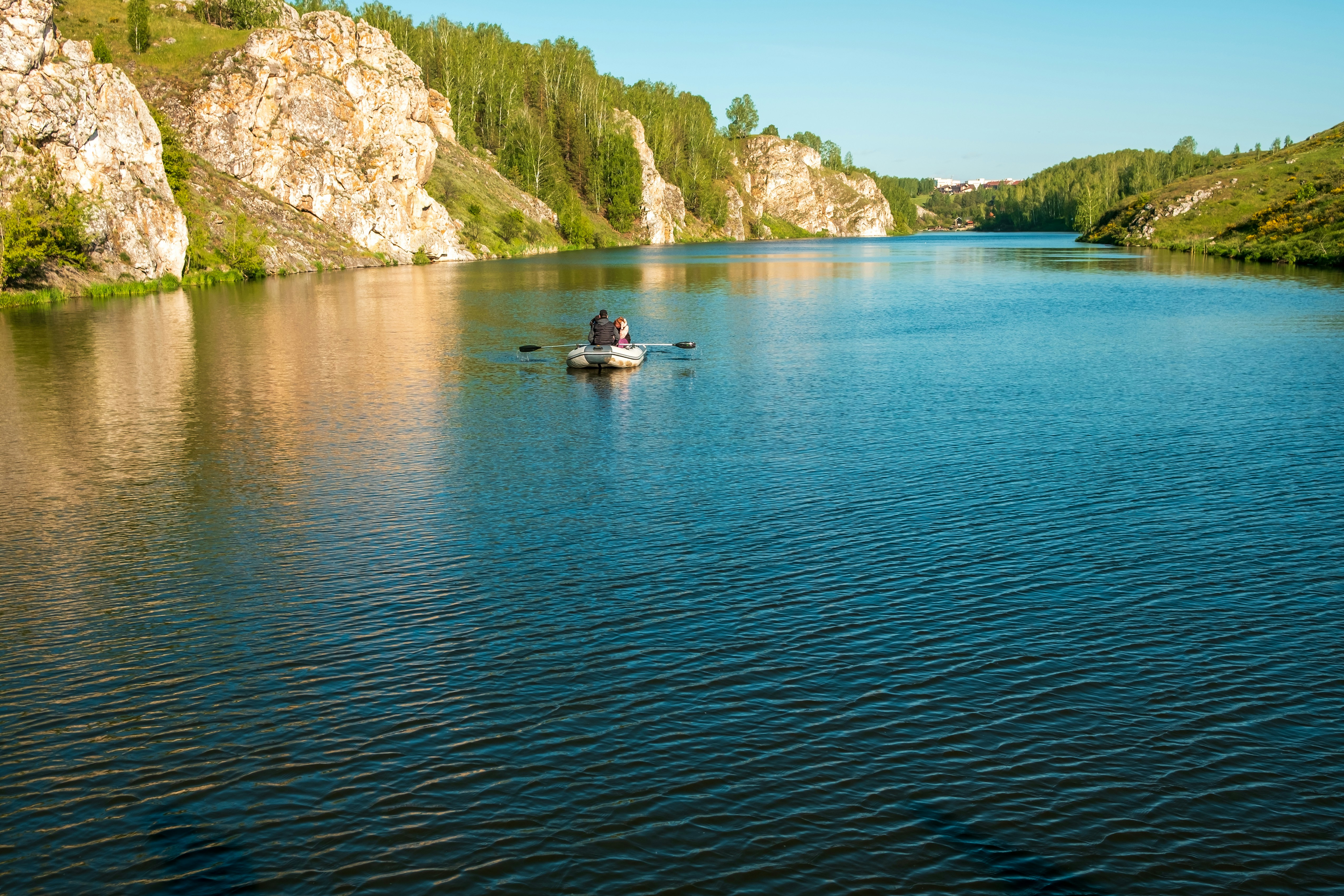A boat floats on a lake between cliffs.
