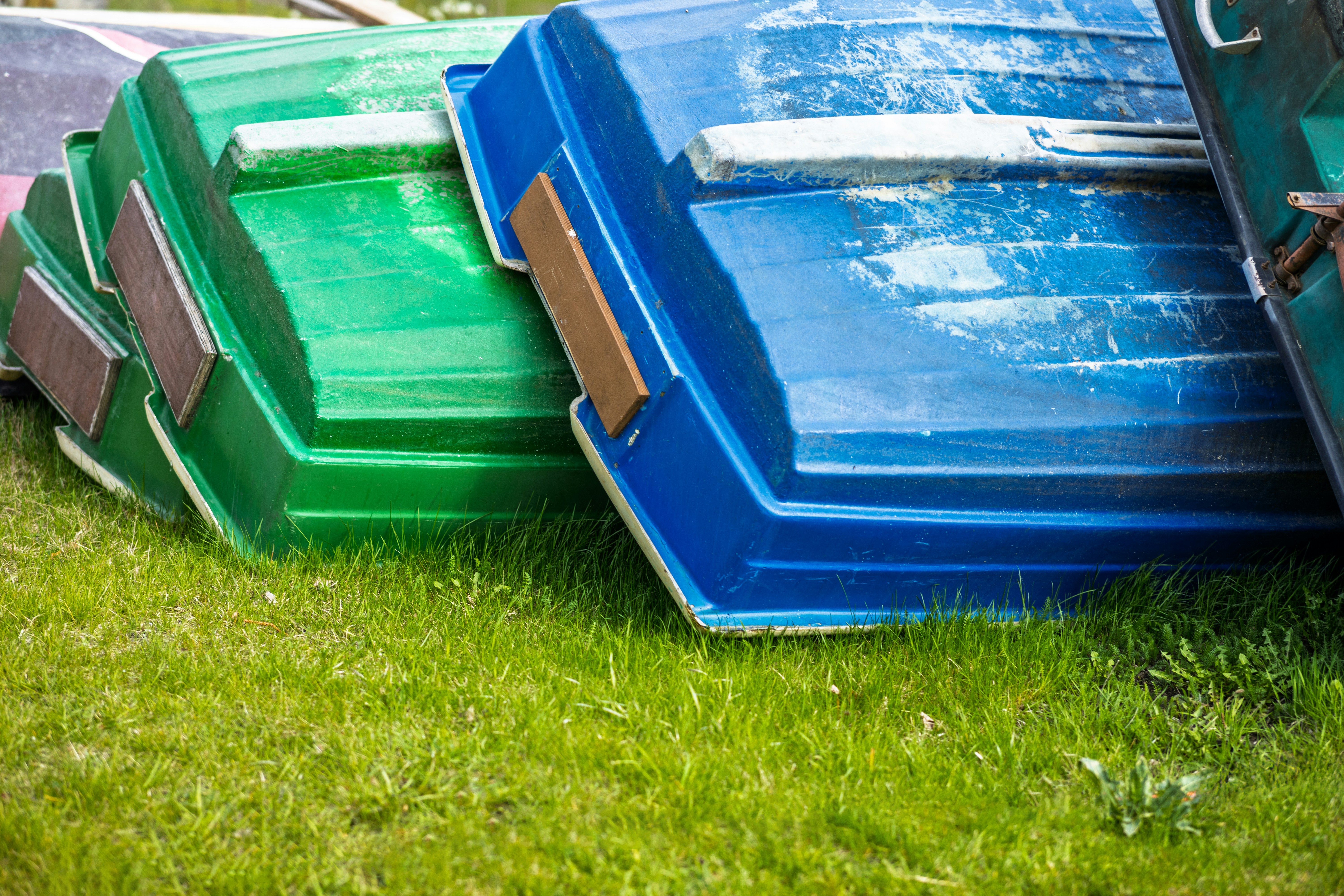 Boats are stacked upside down on the grass.