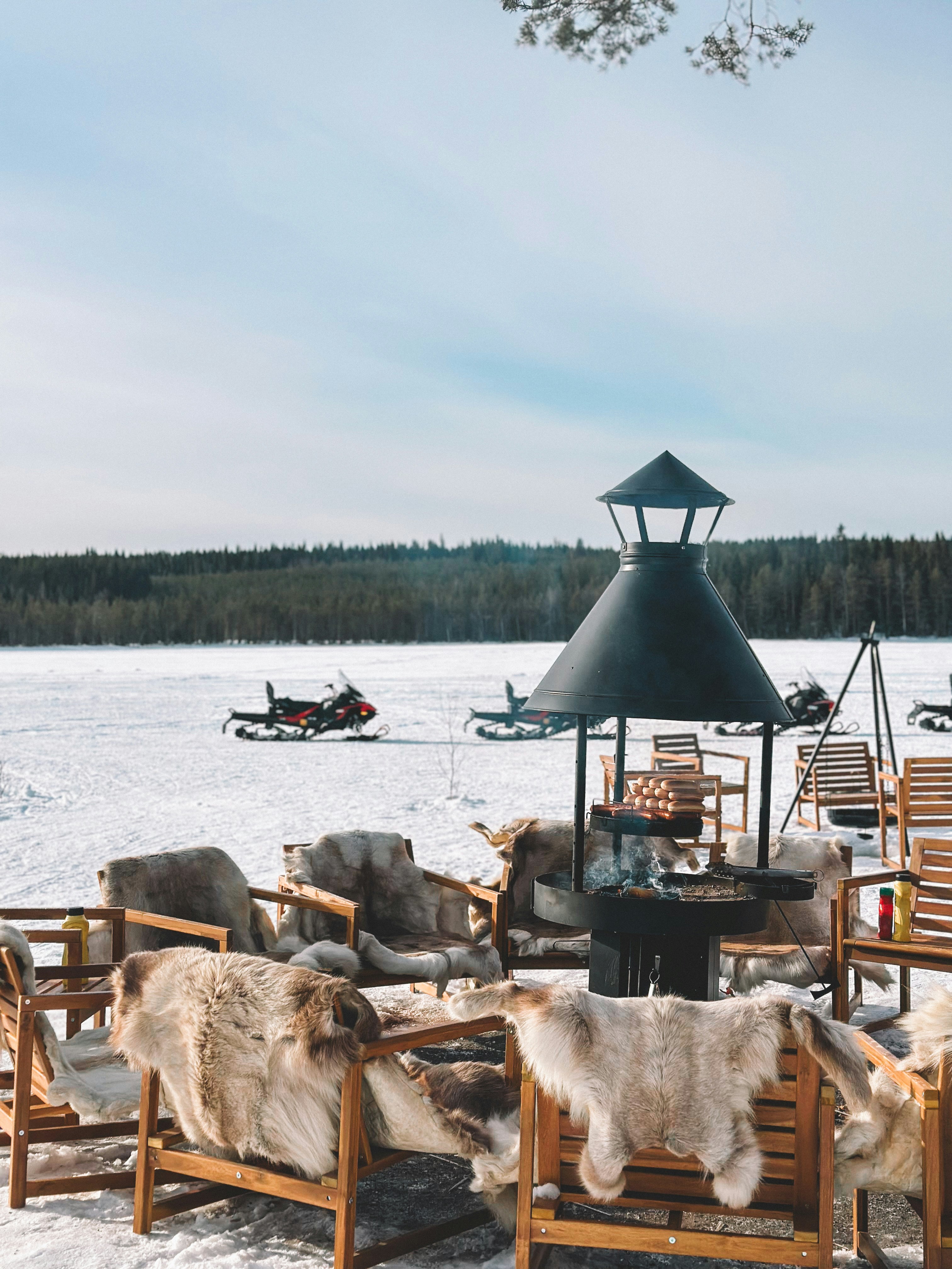 Cozy outdoor seating with snowmobiles on a frozen lake.