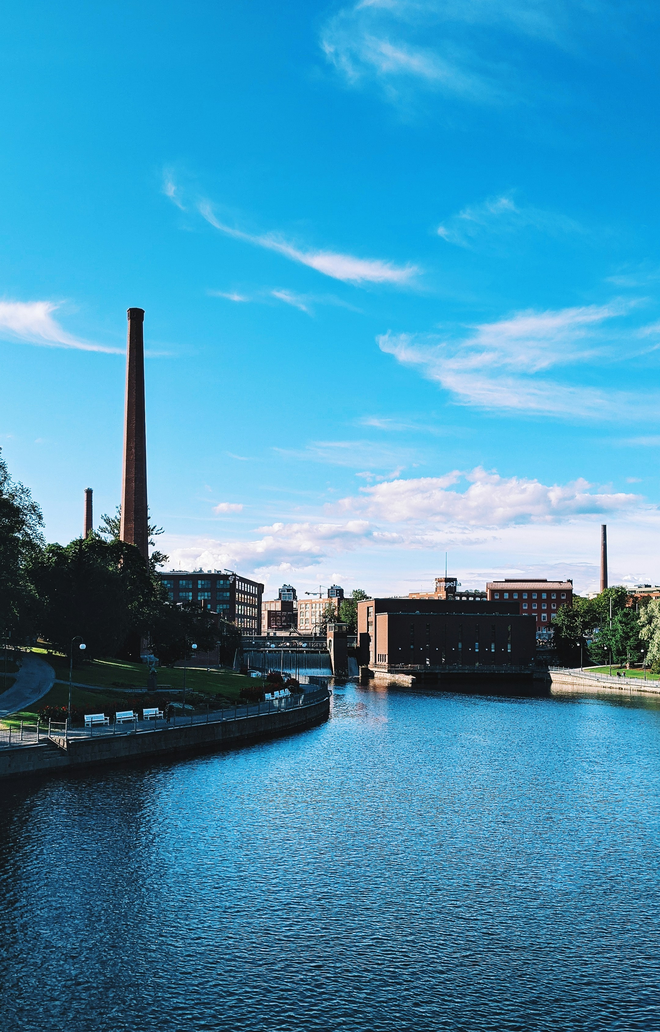 River flows past buildings and a smokestack.