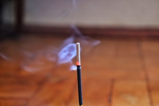 Incense stick burning and emitting smoke.