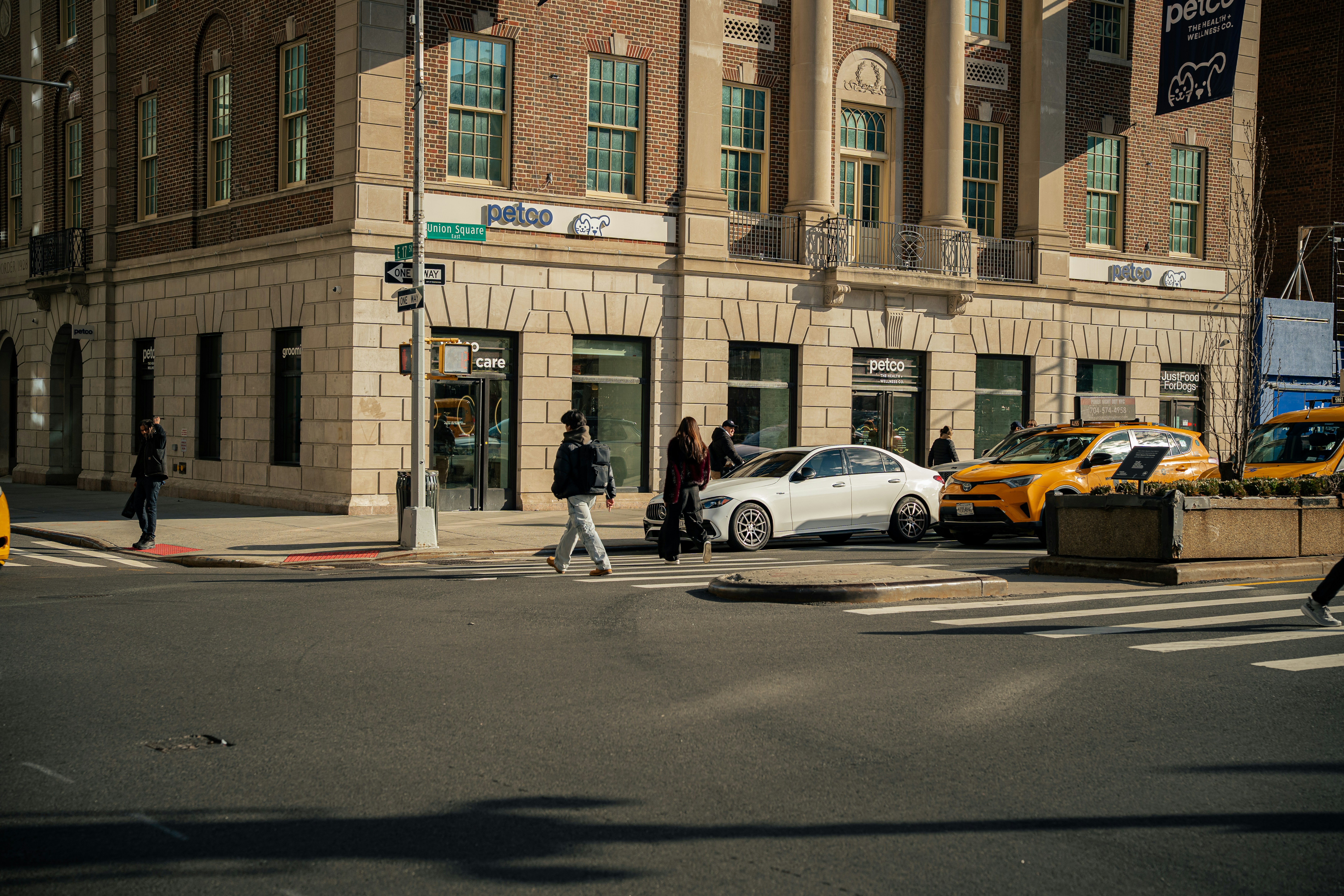 People and cars cross a street in the city.