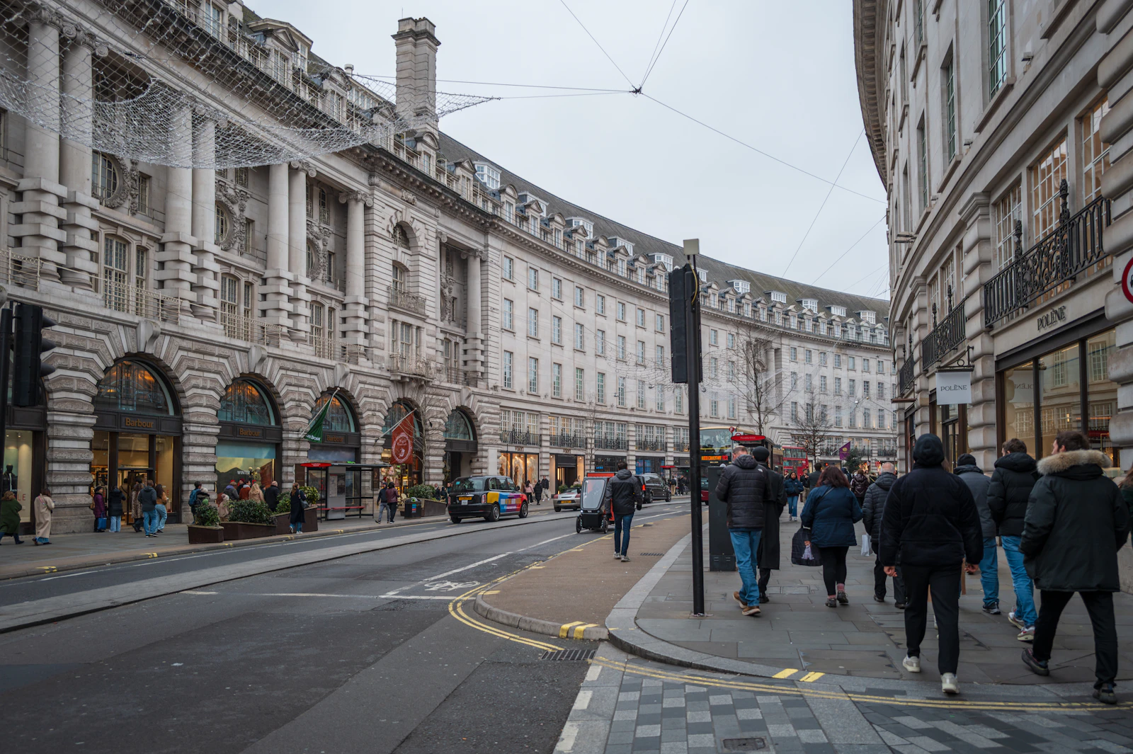 Photograph of People walking along a curved central London street lined with pale stone buildings.