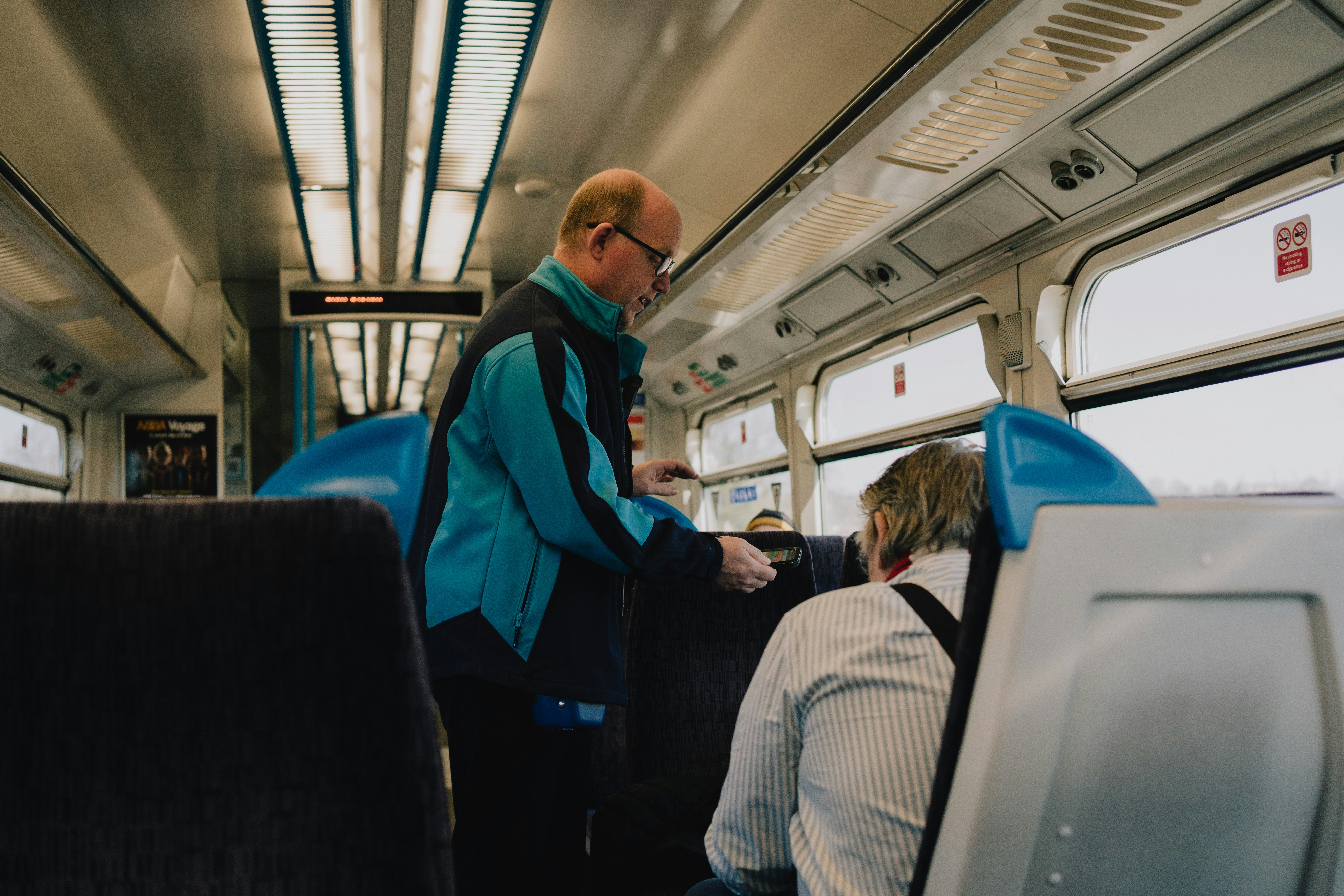 A railway TTE talking to passengers in a train coach, explaining the rules.