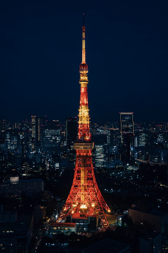 Tokyo Tower illuminated in red and gold above the city at night