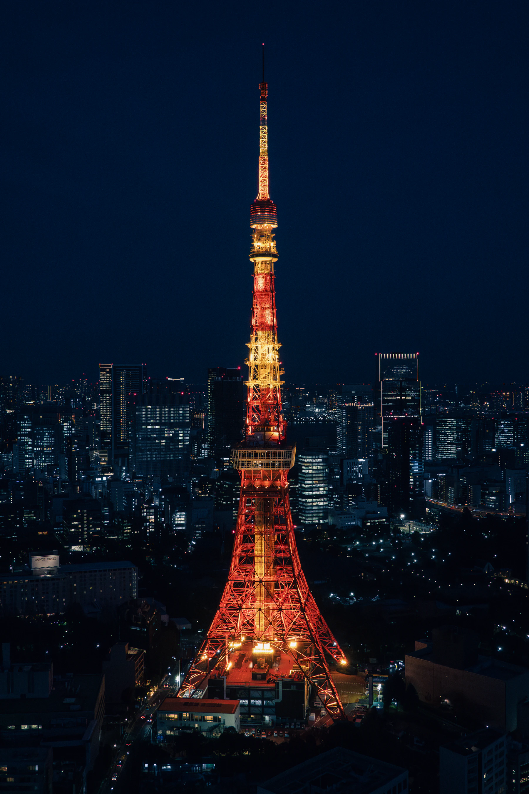 Tokyo Tower illuminated in red and gold above the city at night