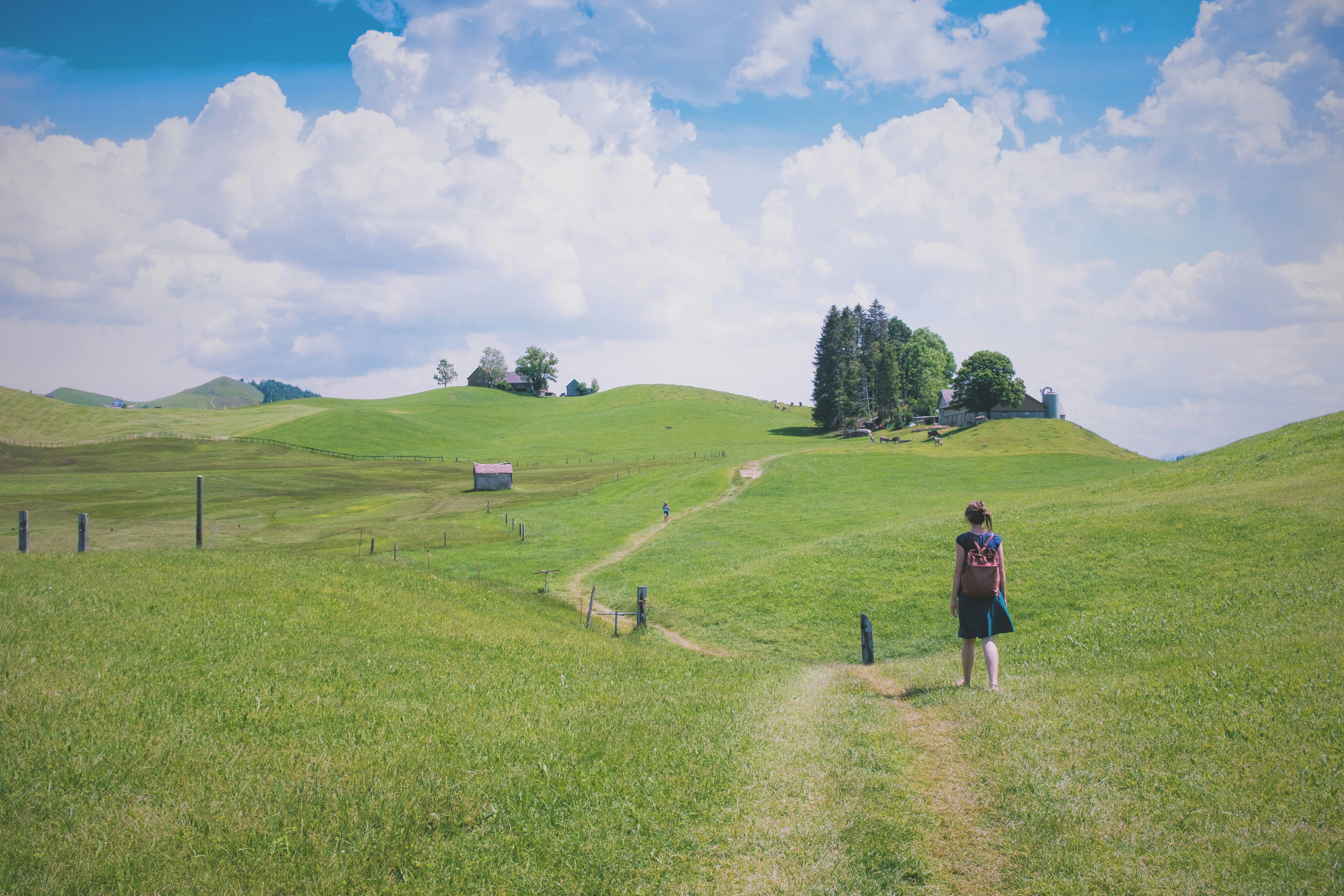 A person hikes through a scenic, green landscape.