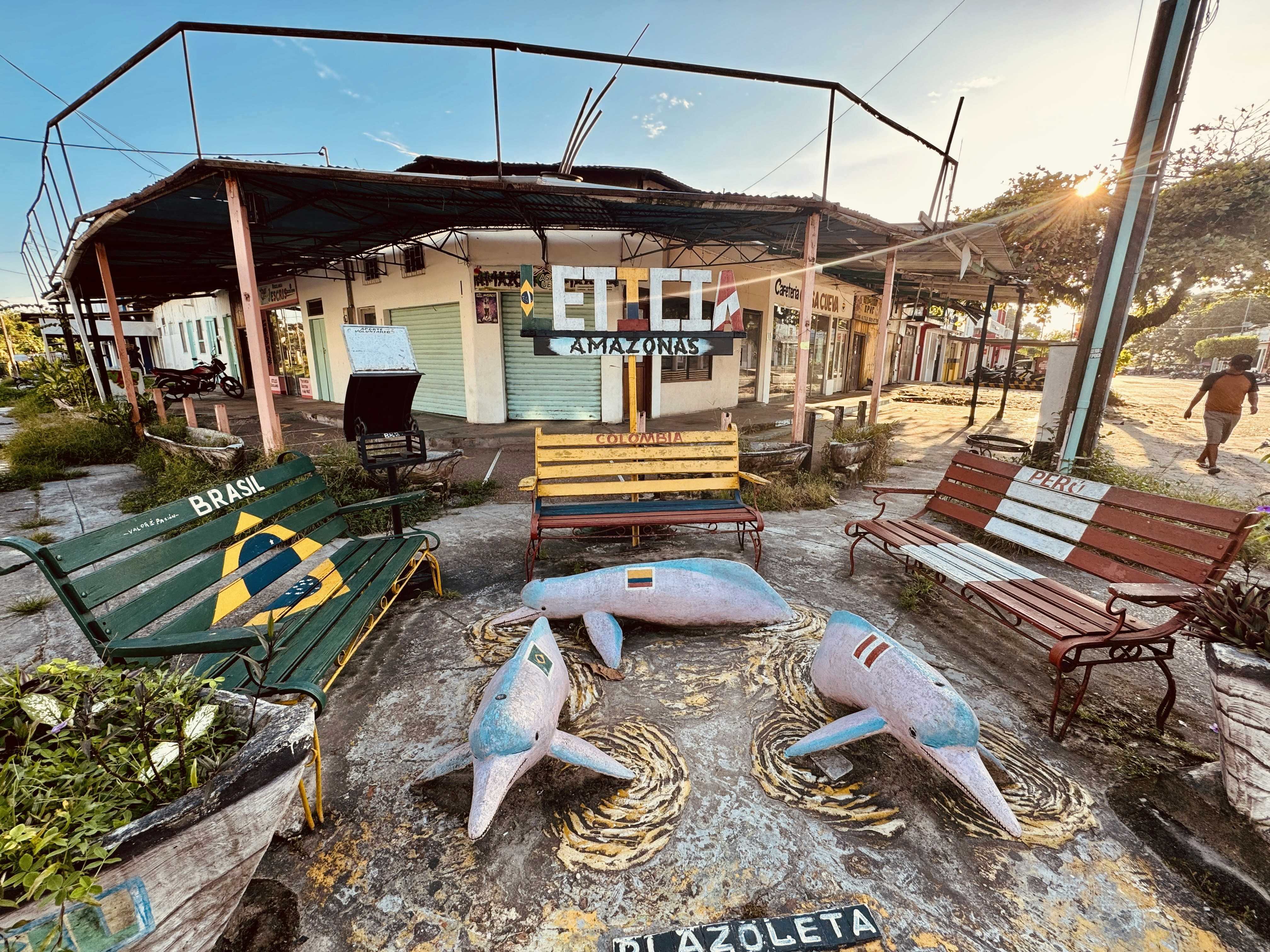 A seaside plaza featuring artistic benches and statues.