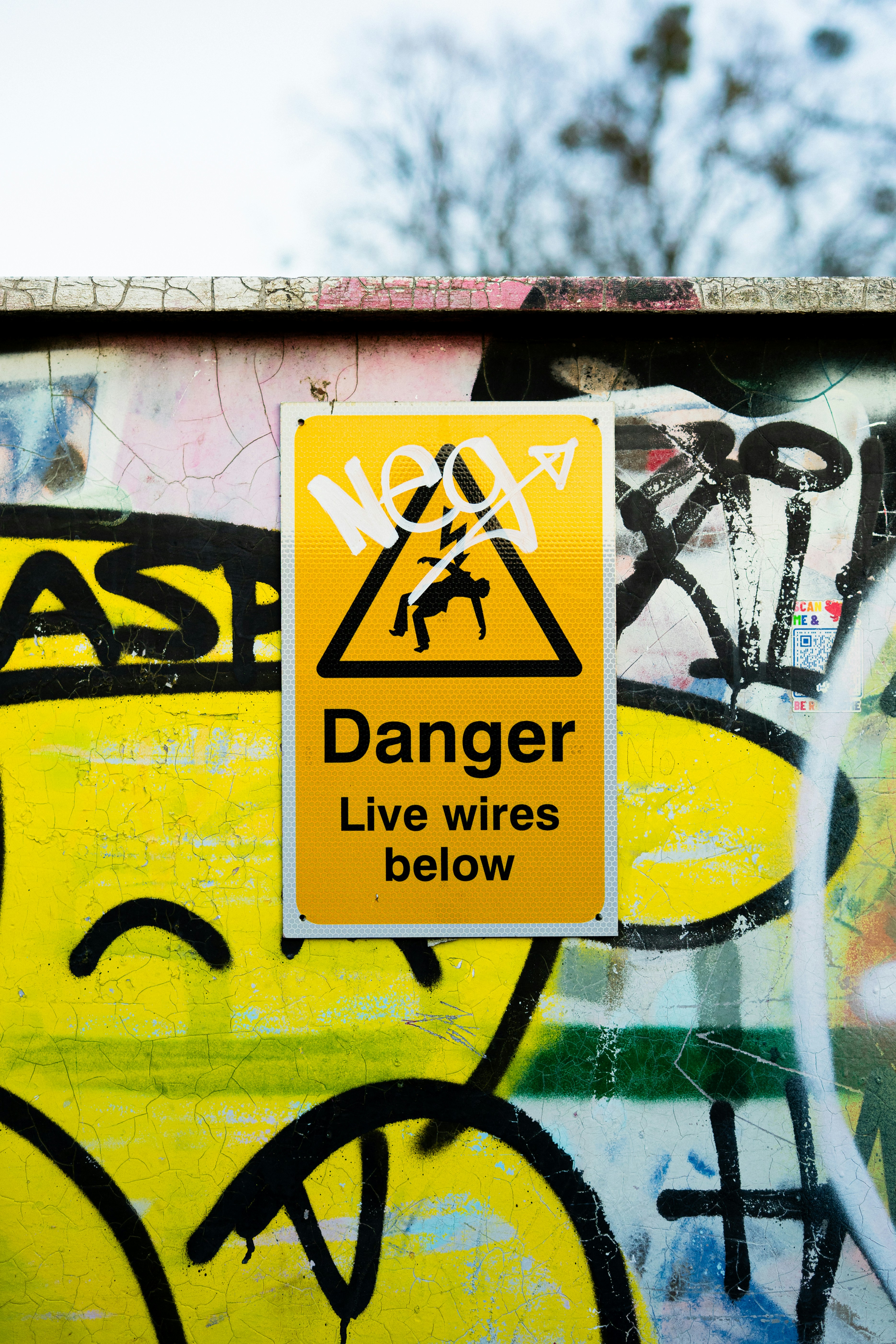 Danger: live wires below on graffiti-covered wall
