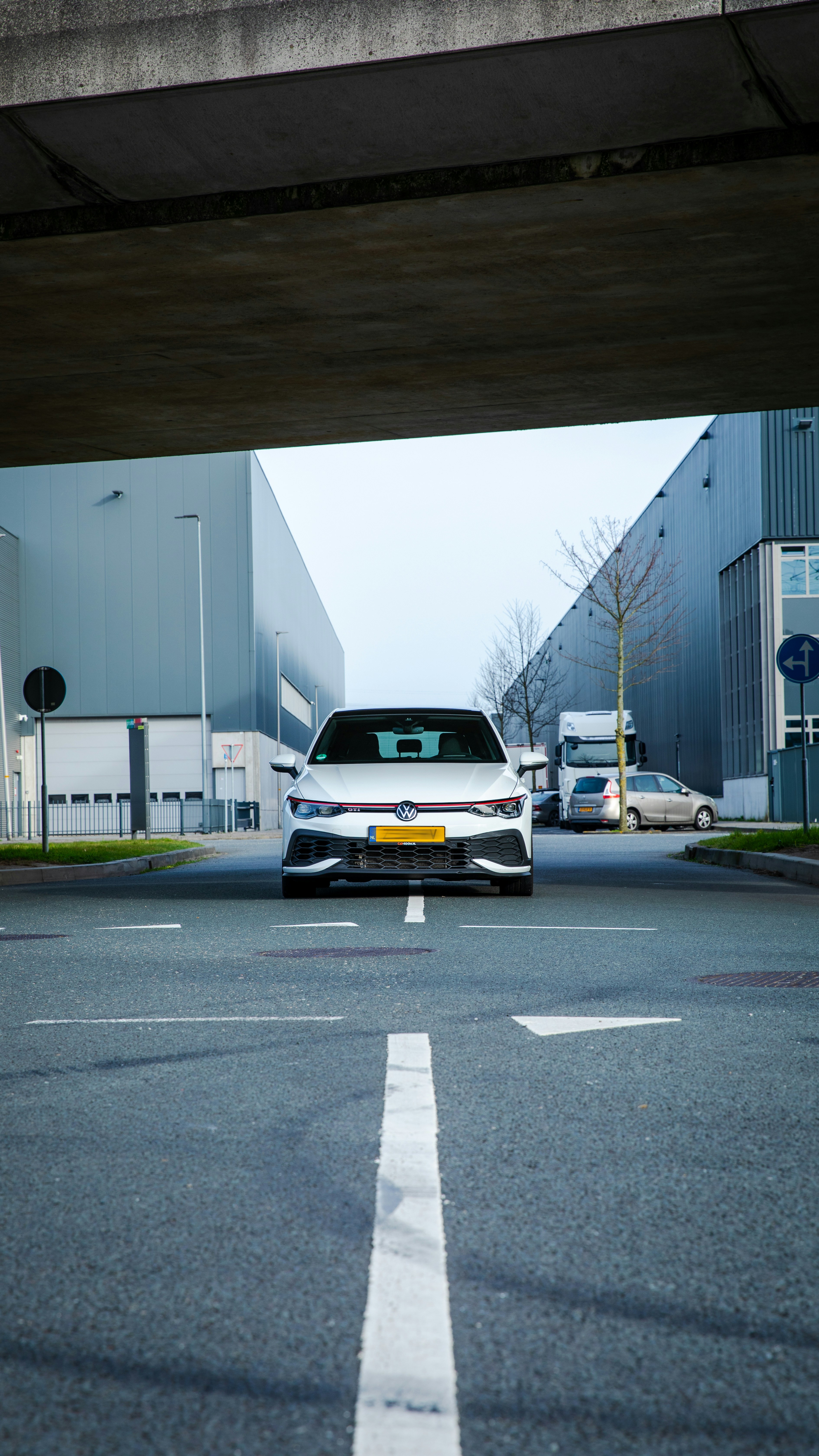 A white car faces the camera on an asphalt road.
