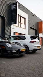 Black porsche and white car parked together.