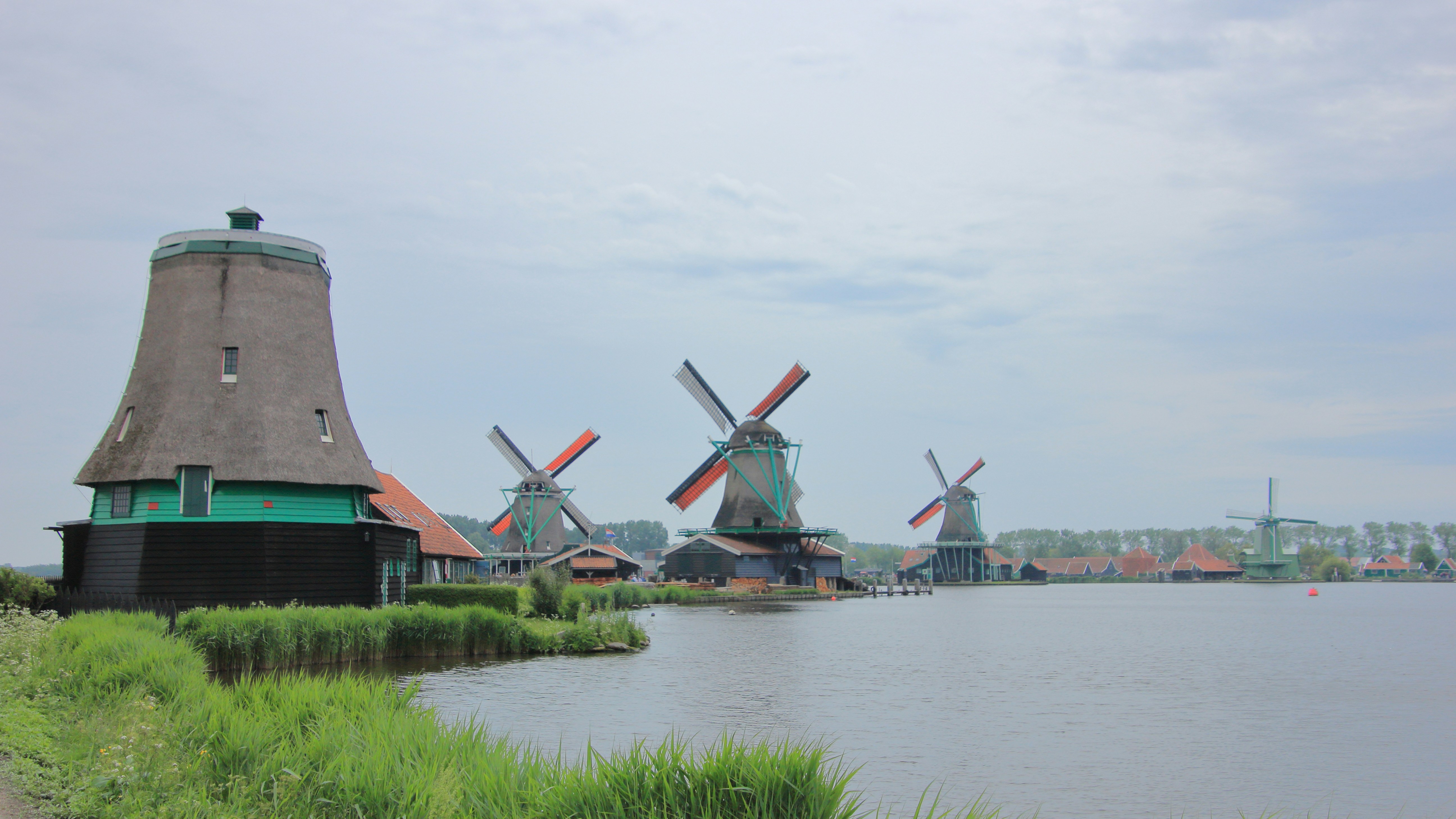 Windmühlen stehen in der Nähe des Wassers.