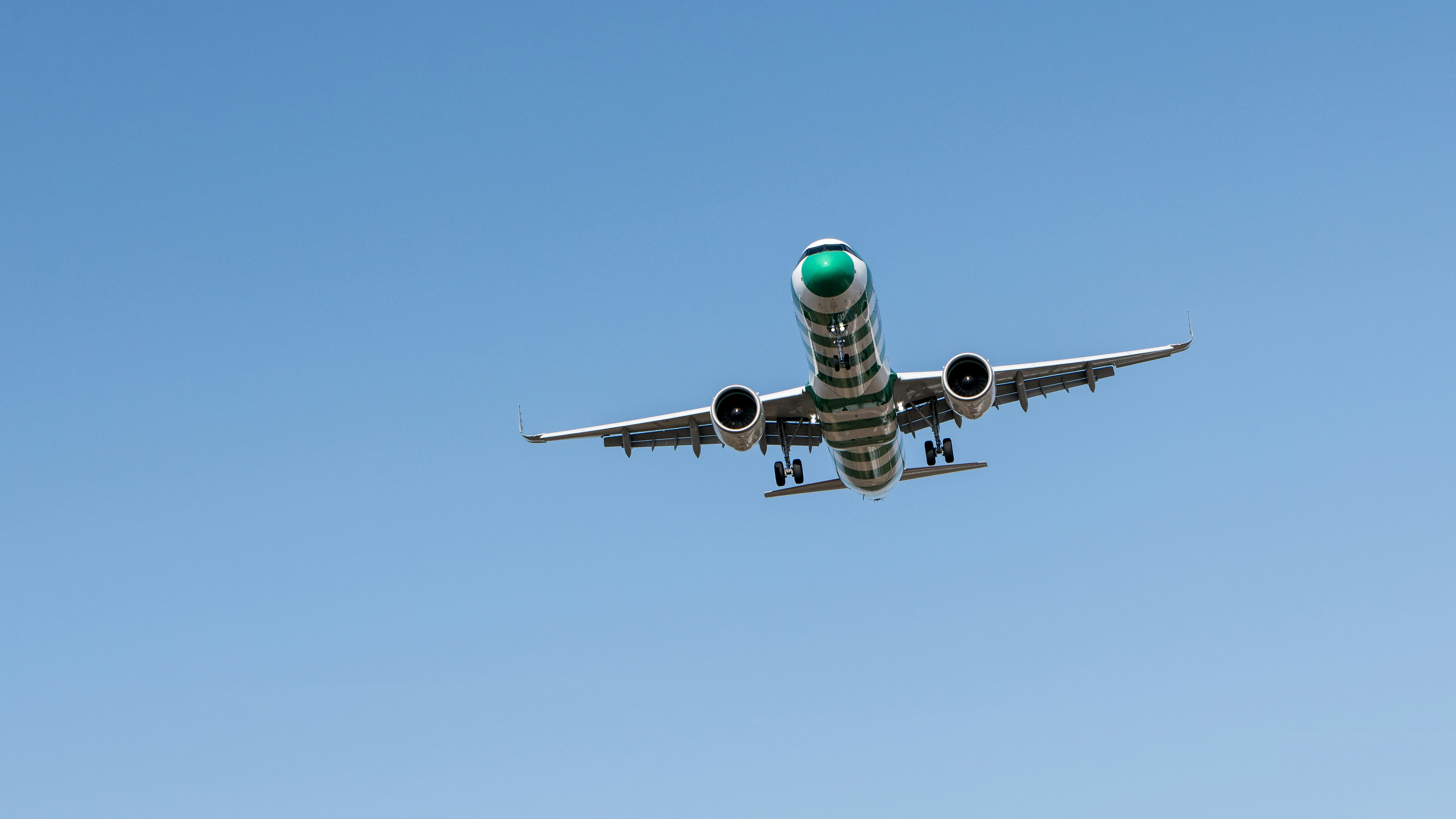 Airplane is landing in clear blue sky.