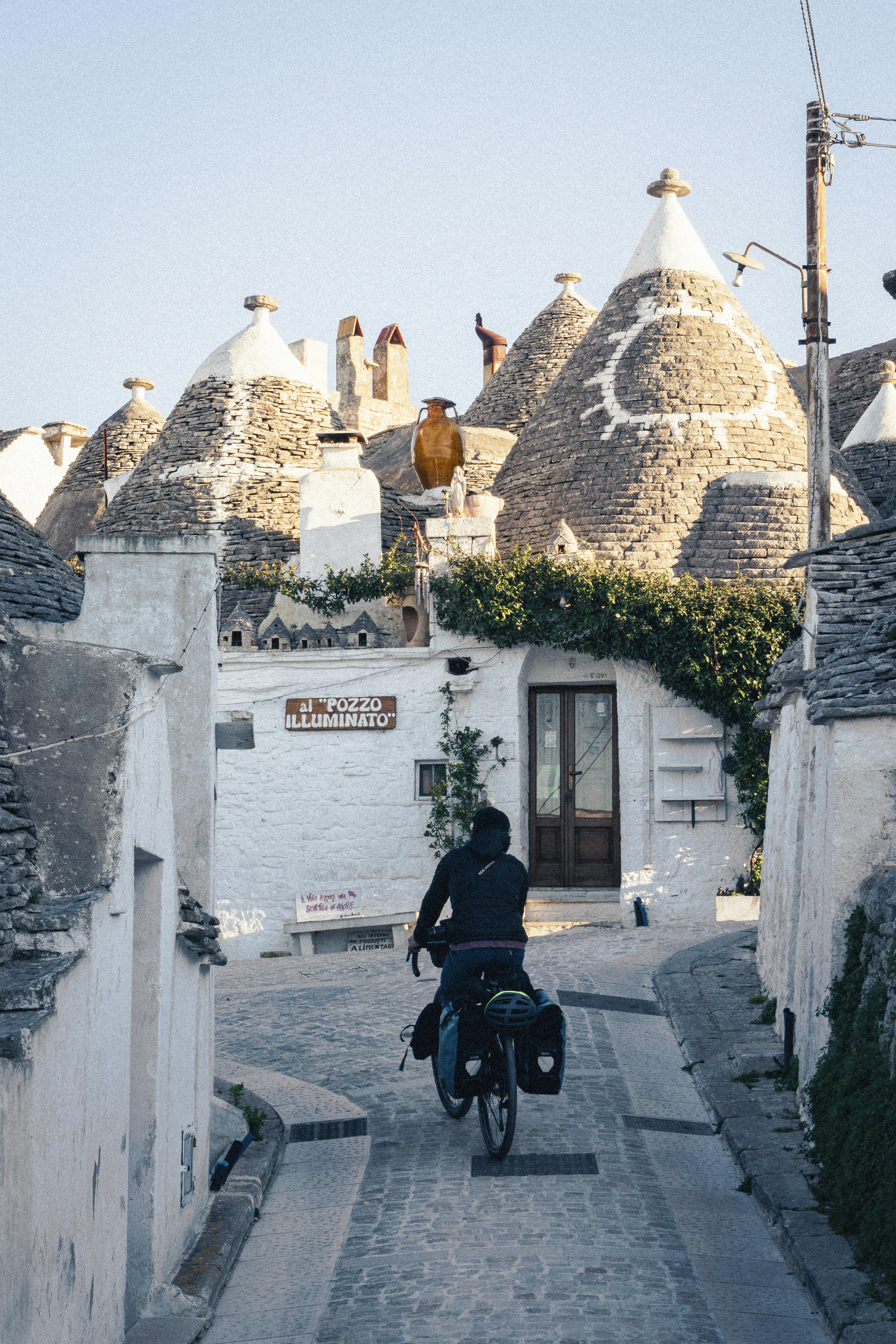 A cyclist rides past unique trulli houses.