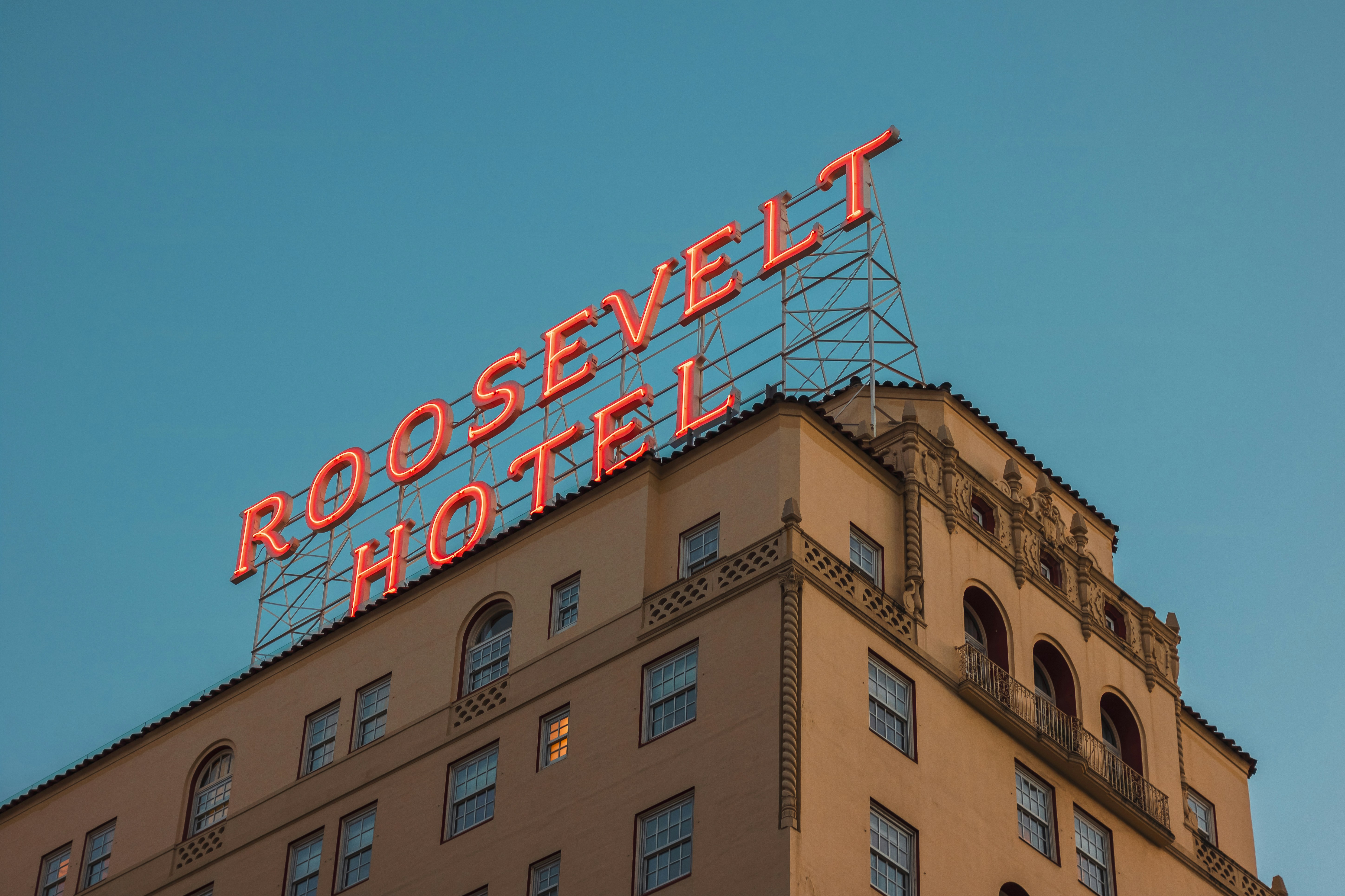 The roosevelt hotel sign is bright against the blue sky.