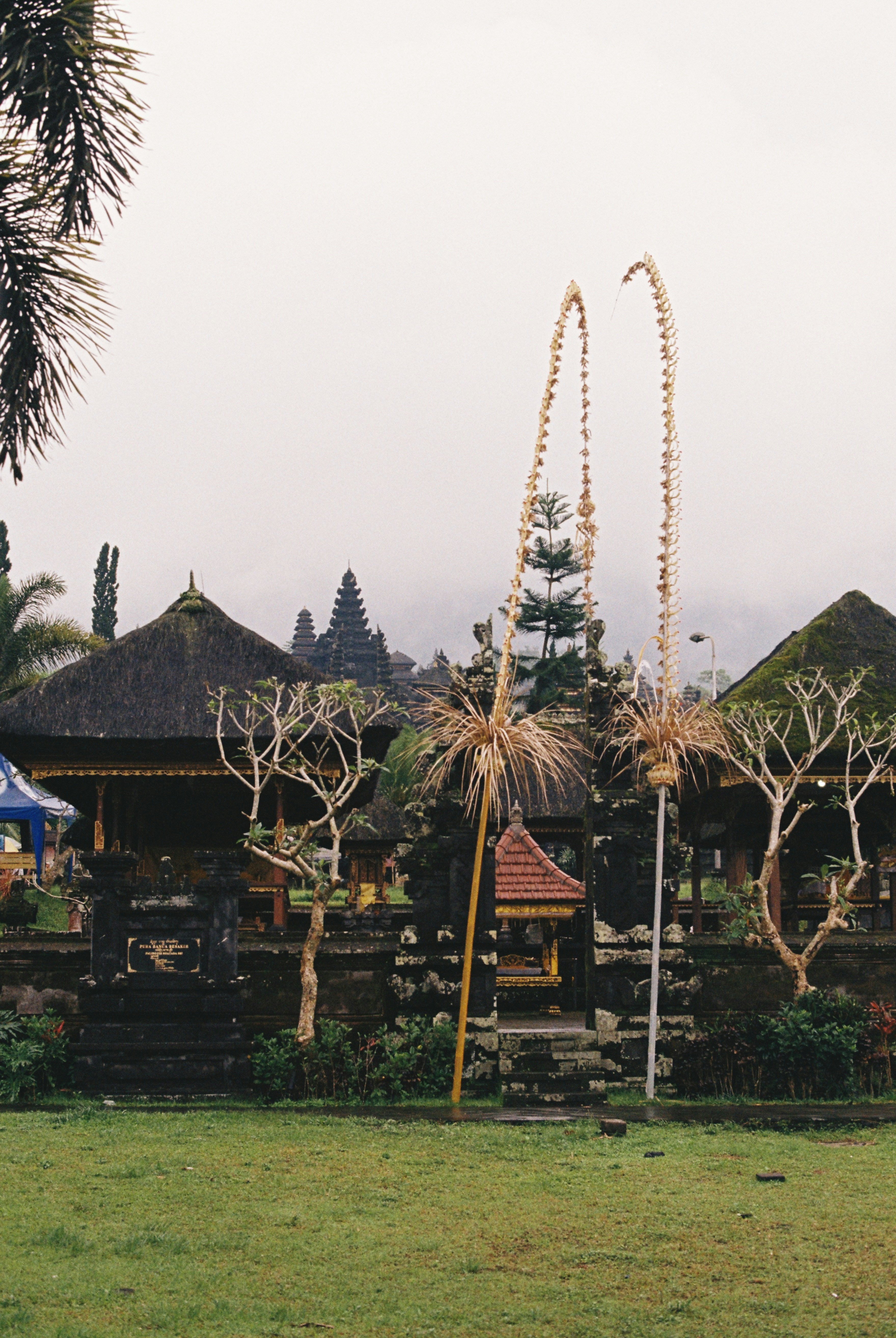 Pura tradisional Bali berdiri di tengah lanskap berawan.