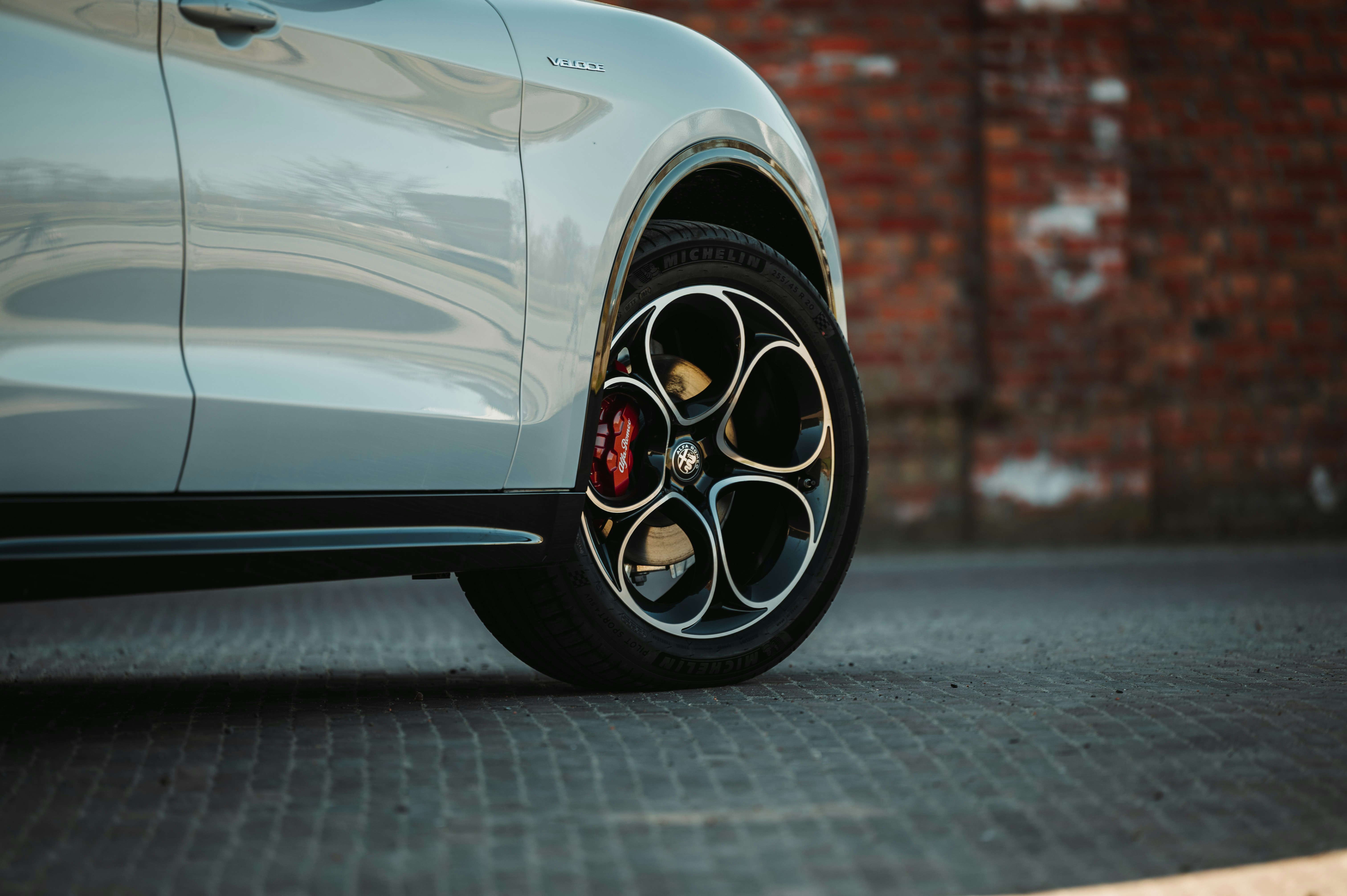 A car's wheel parked near a brick wall.