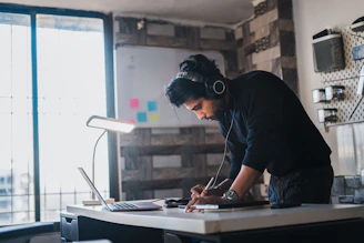 A man works at a desk with headphones.