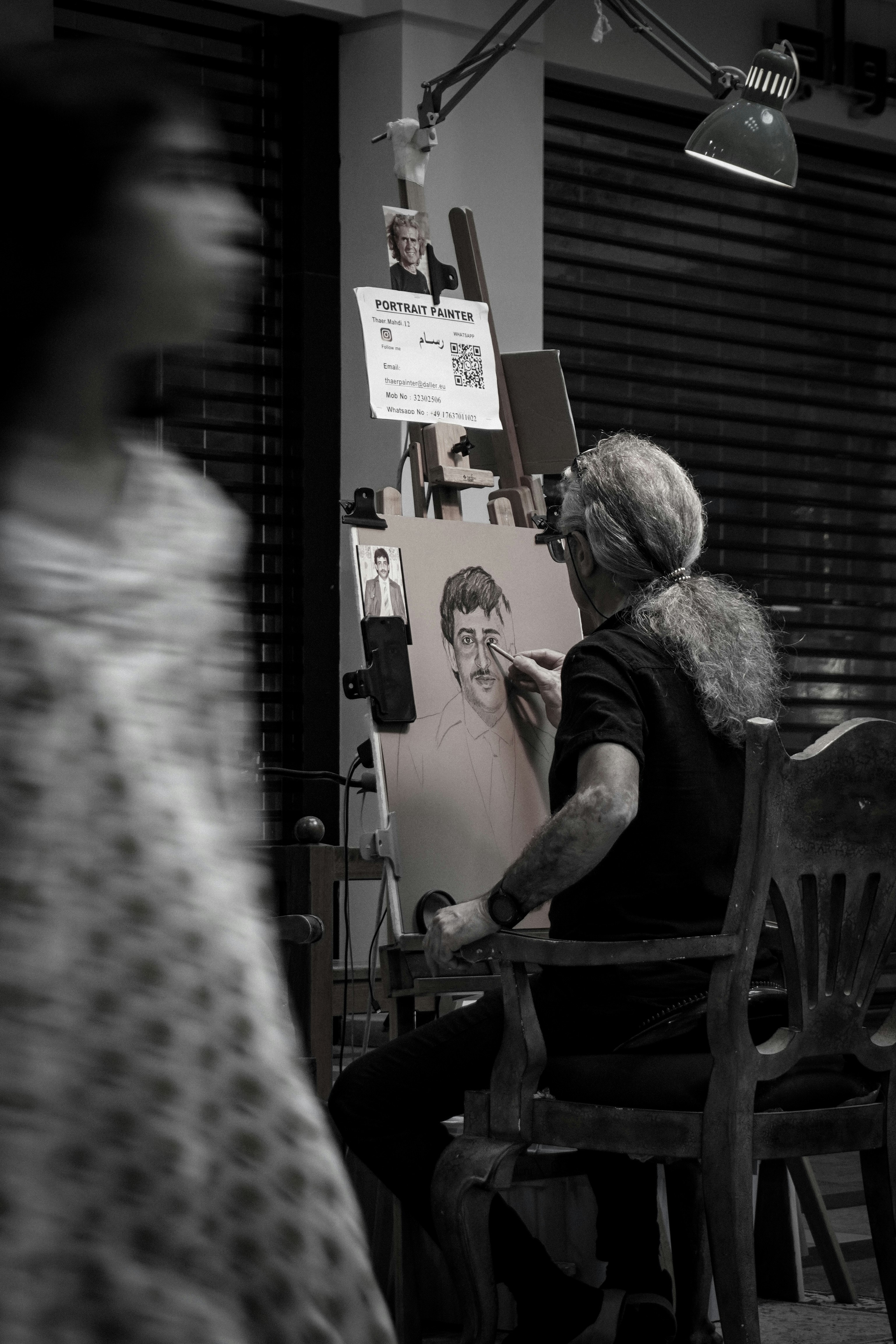 An artist works on a portrait at a street stall.